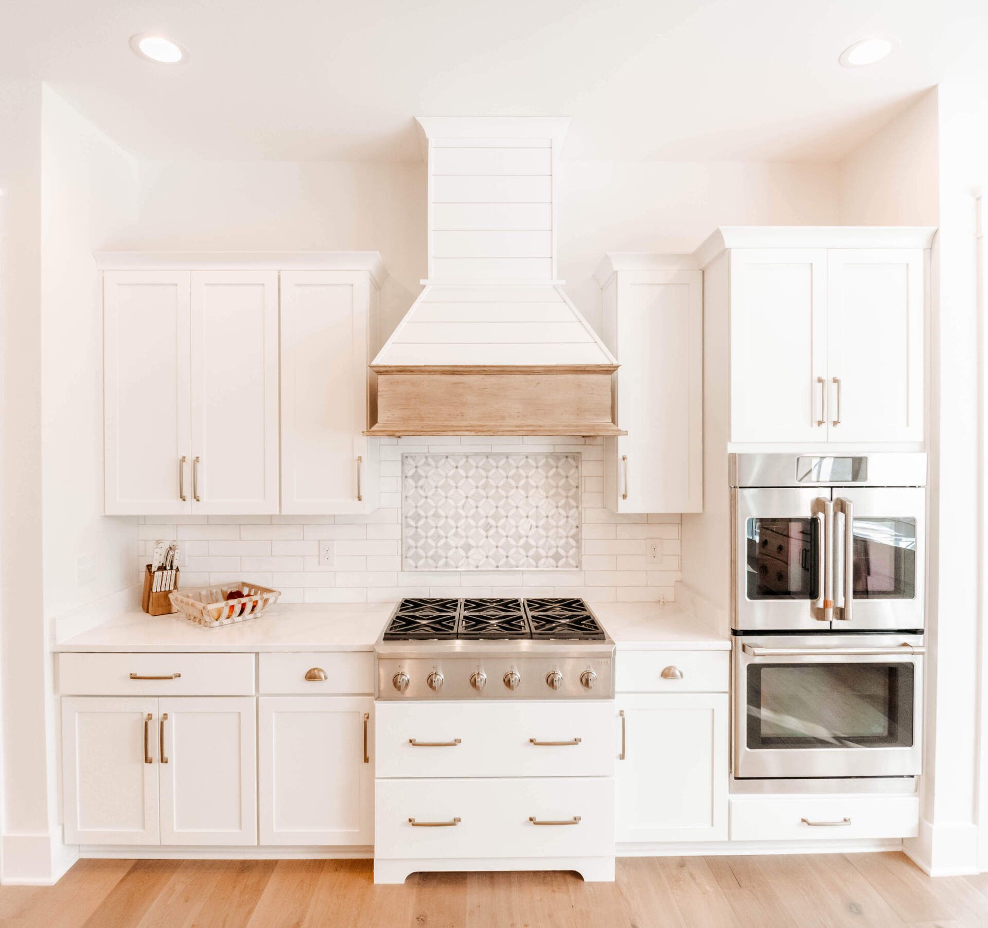 Bright white modern kitchen with island, stainless steel appliances, and wood floor