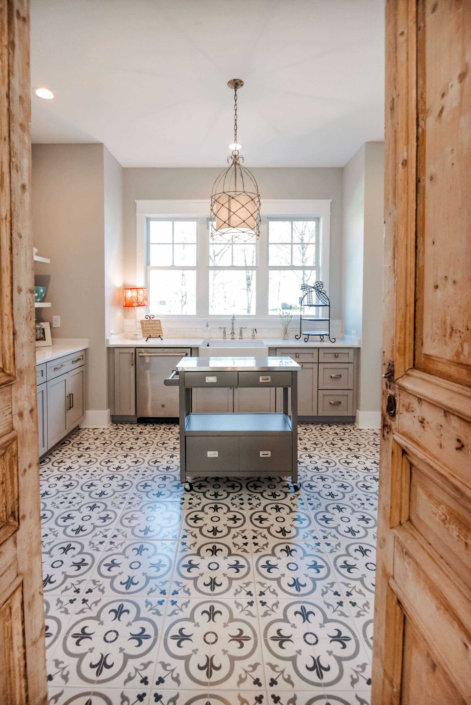 Bright kitchen with patterned tile floor, central island, white cabinets, and window over the sink