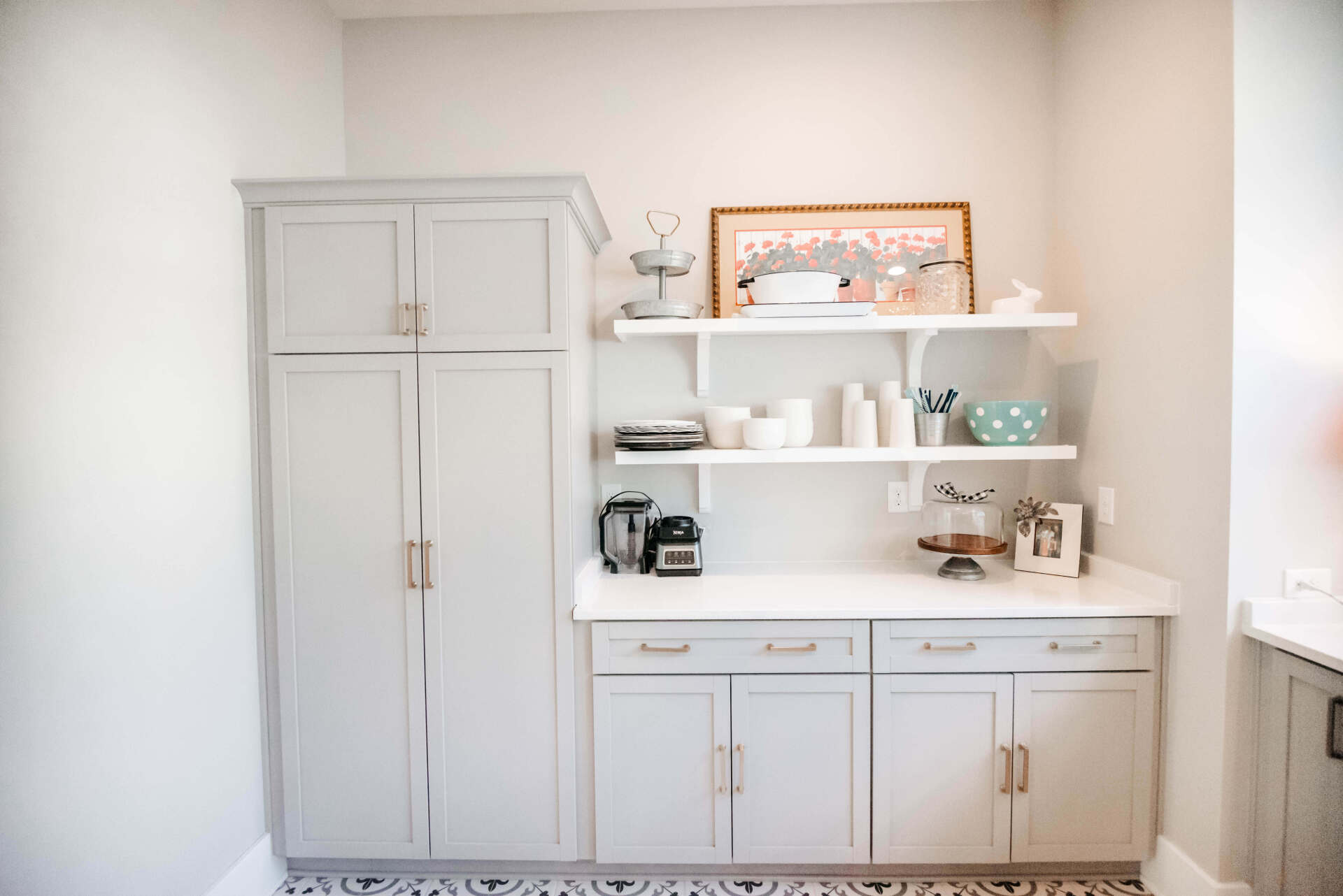White built-in storage cabinets and shelves in a bright kitchen or pantry with small decor items.