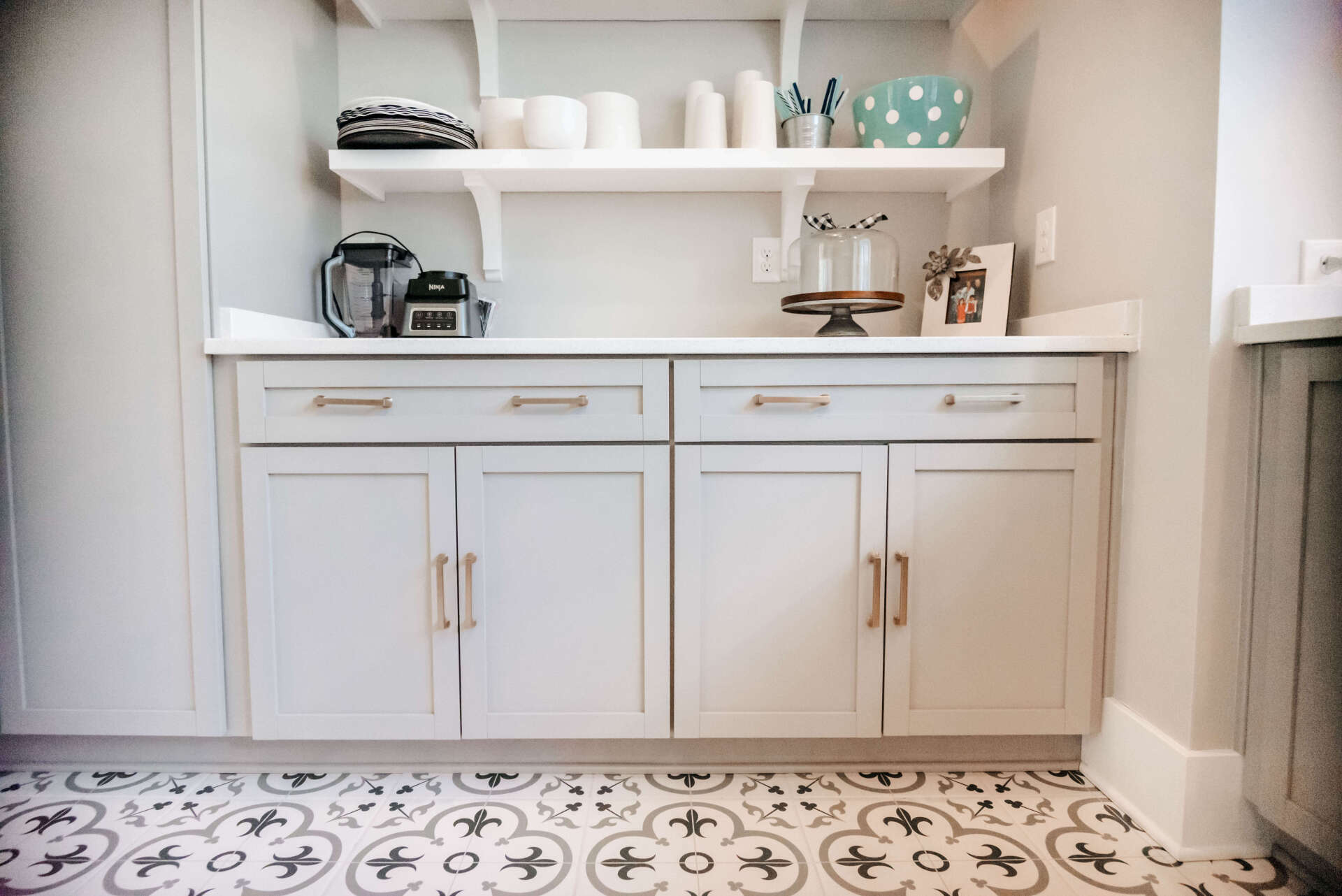 Built-in bathroom vanity with white cabinets, open shelves, and patterned tile floor
