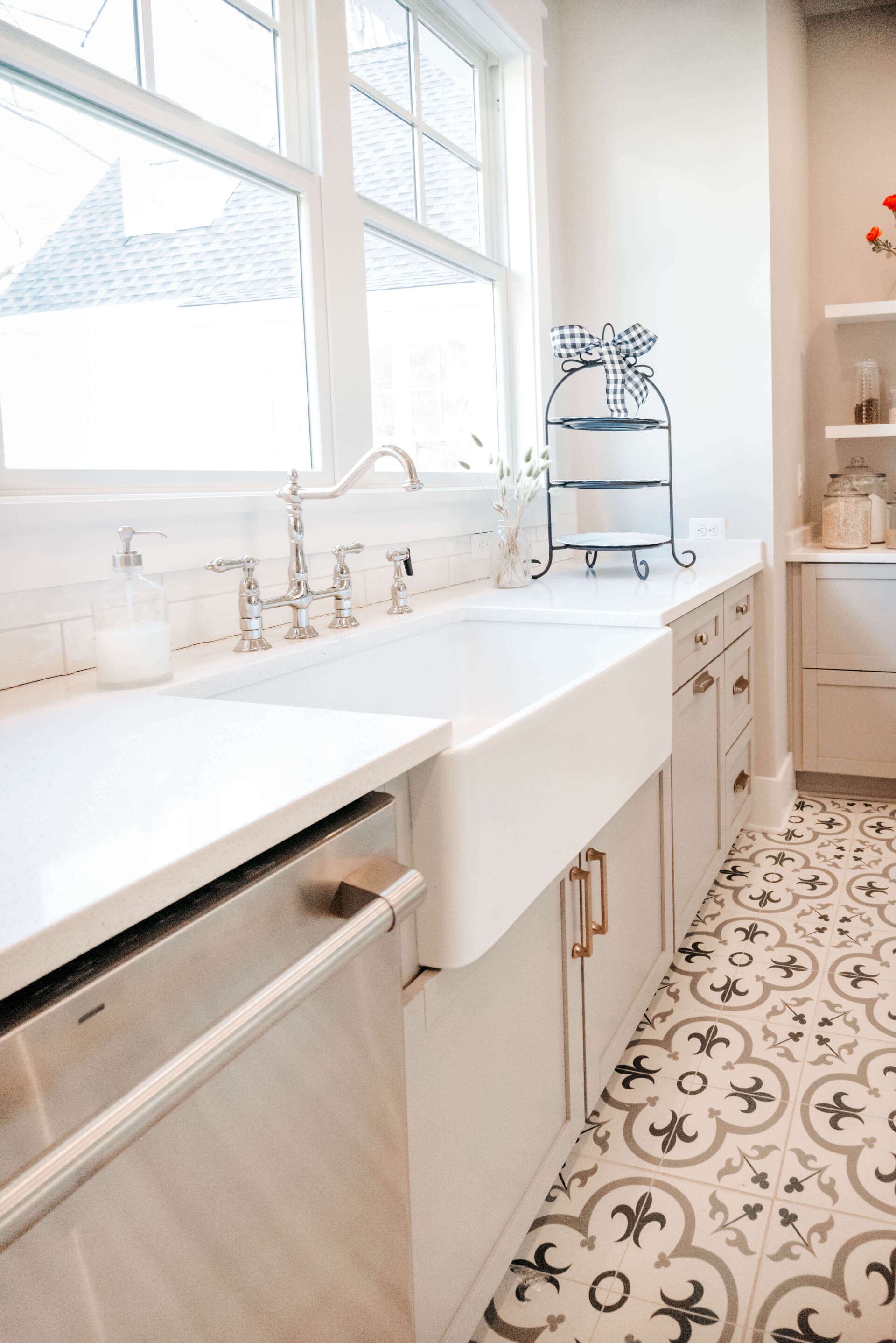 Bright white kitchen with farmhouse sink, window, and patterned tile floor