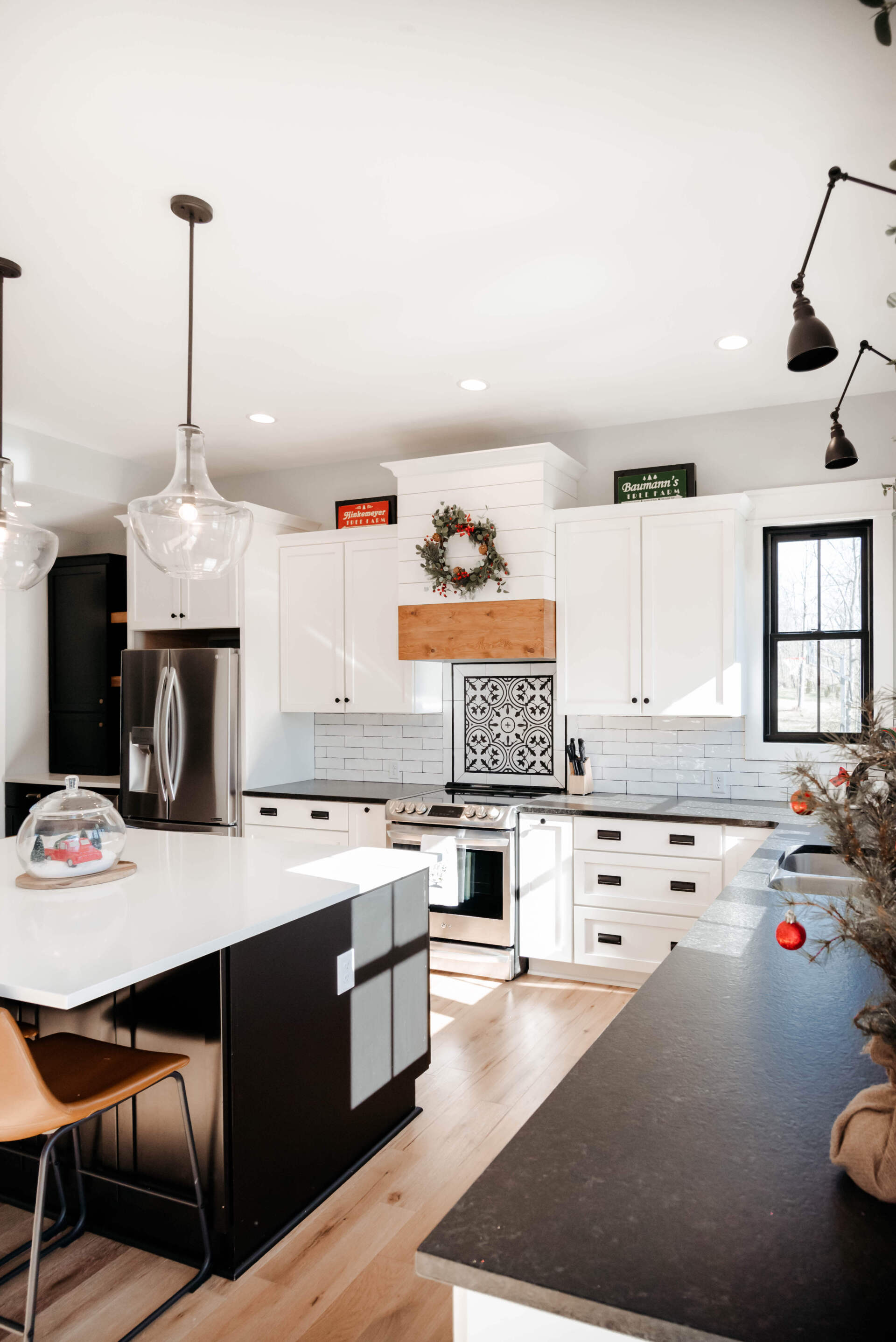 Bright modern kitchen with white cabinets, black countertops, stainless fridge, and a center island