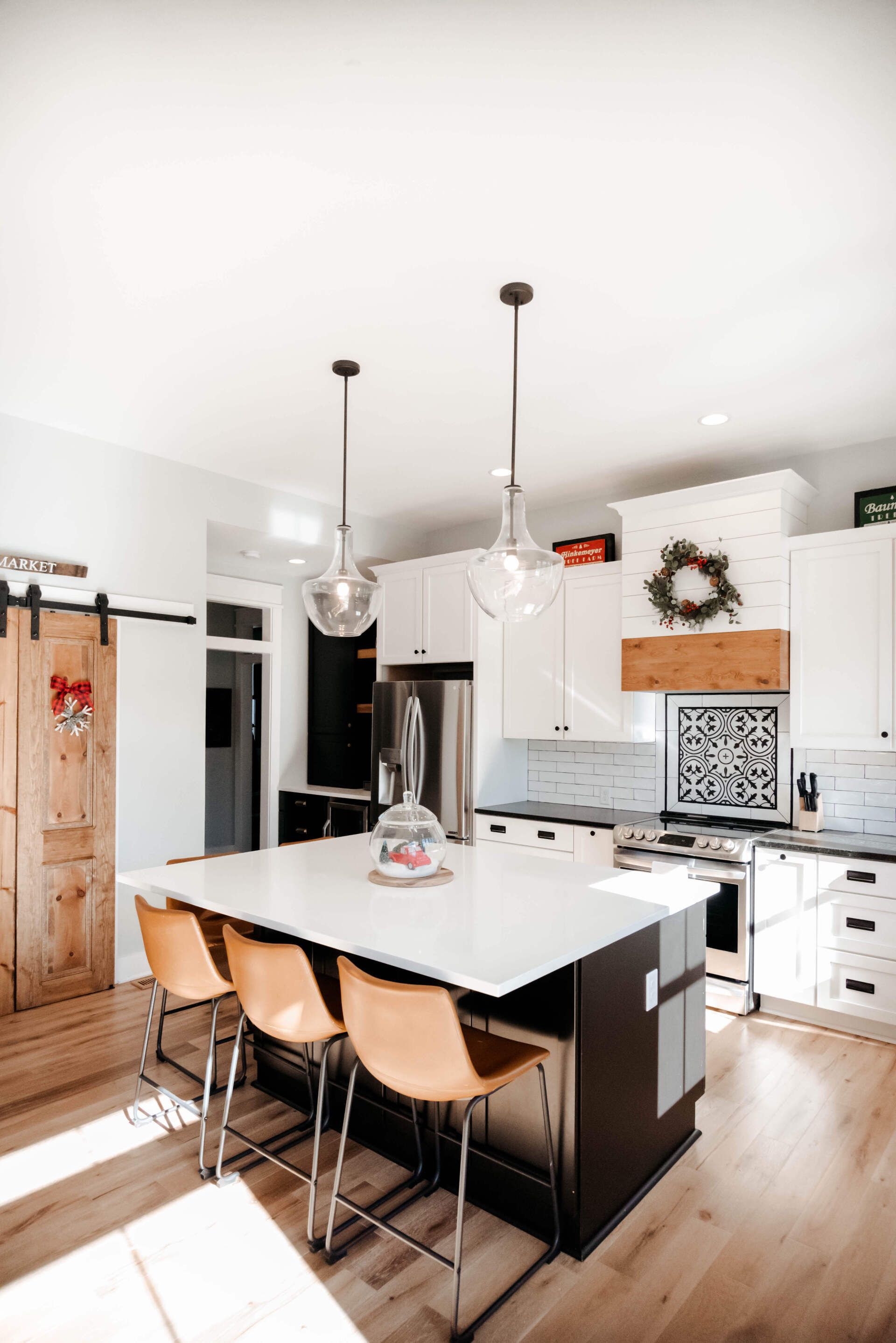 Bright modern kitchen with white cabinets, island, pendant lights, and wooden bar stools