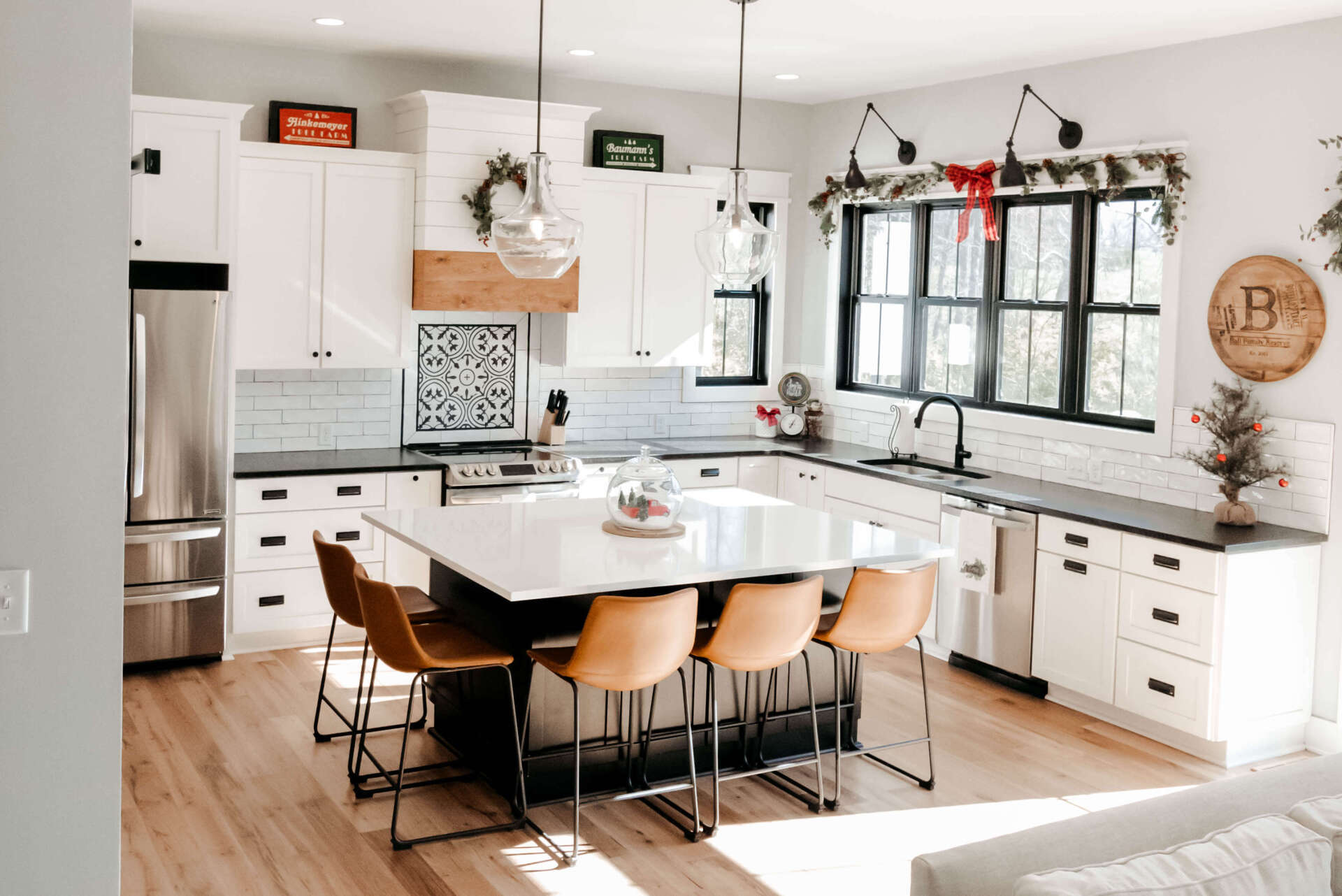 Bright modern kitchen with white cabinets, black island, and wooden stools under large windows