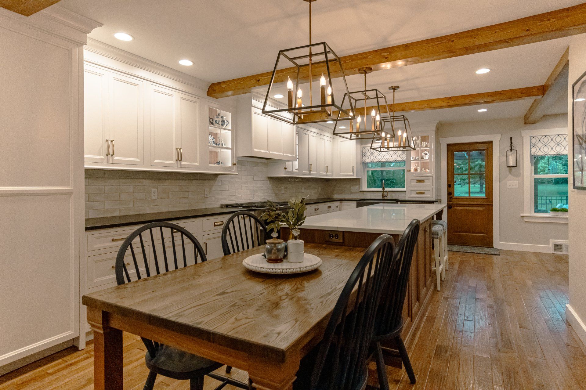Bright farmhouse kitchen with white cabinets, wood island table, and pendant lights