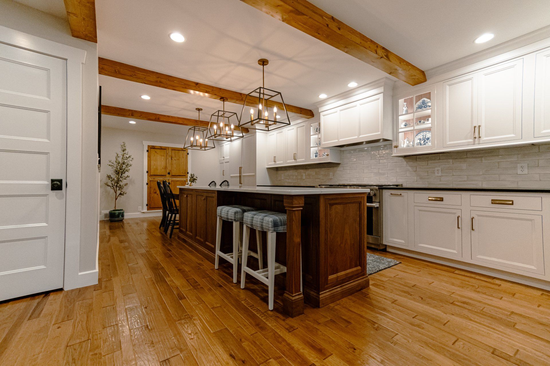 Bright modern kitchen with wood island, white cabinets, hanging pendant lights, and hardwood floors.