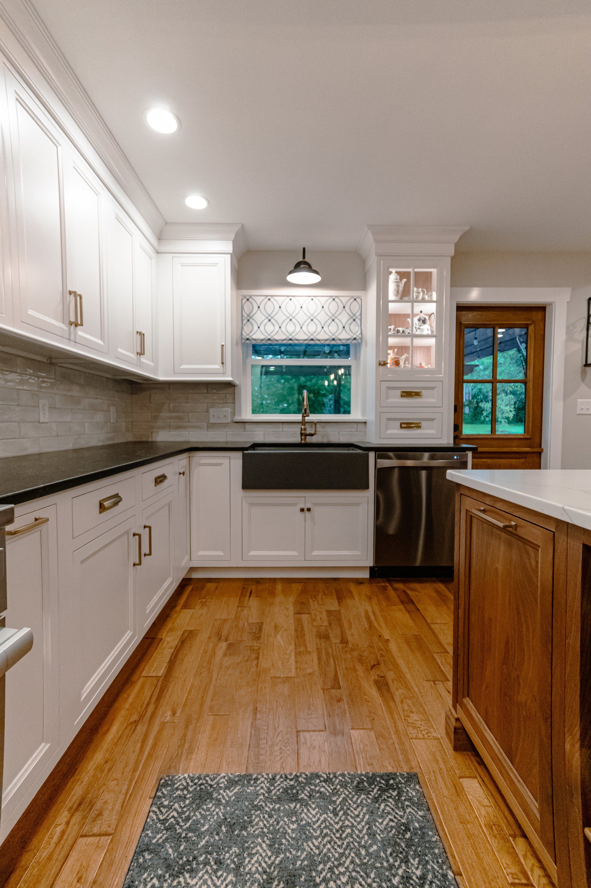 Bright modern kitchen with white cabinets, wood island, and patterned backsplash.
