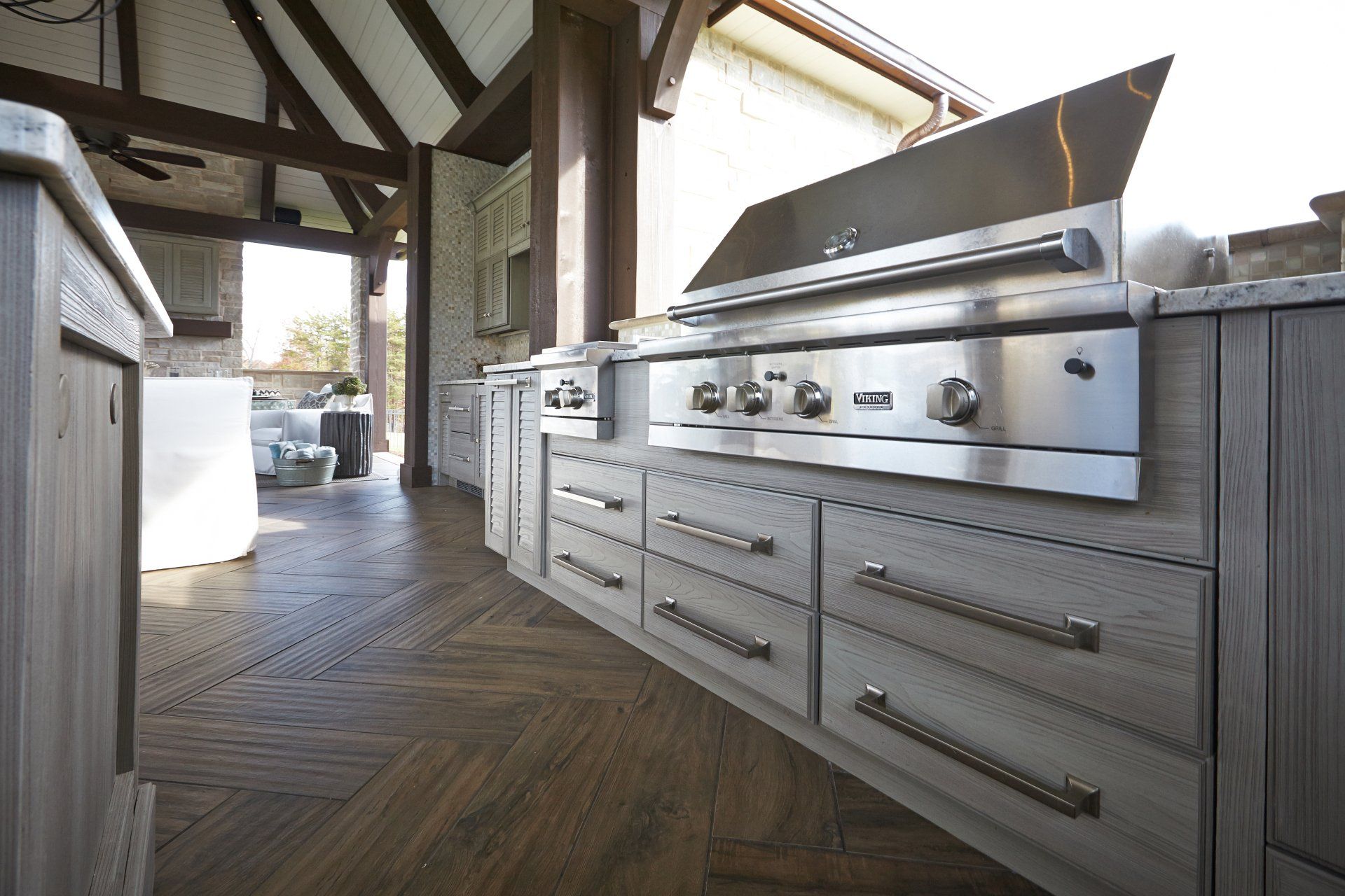 Outdoor kitchen with stainless steel grill and cabinets on a covered patio