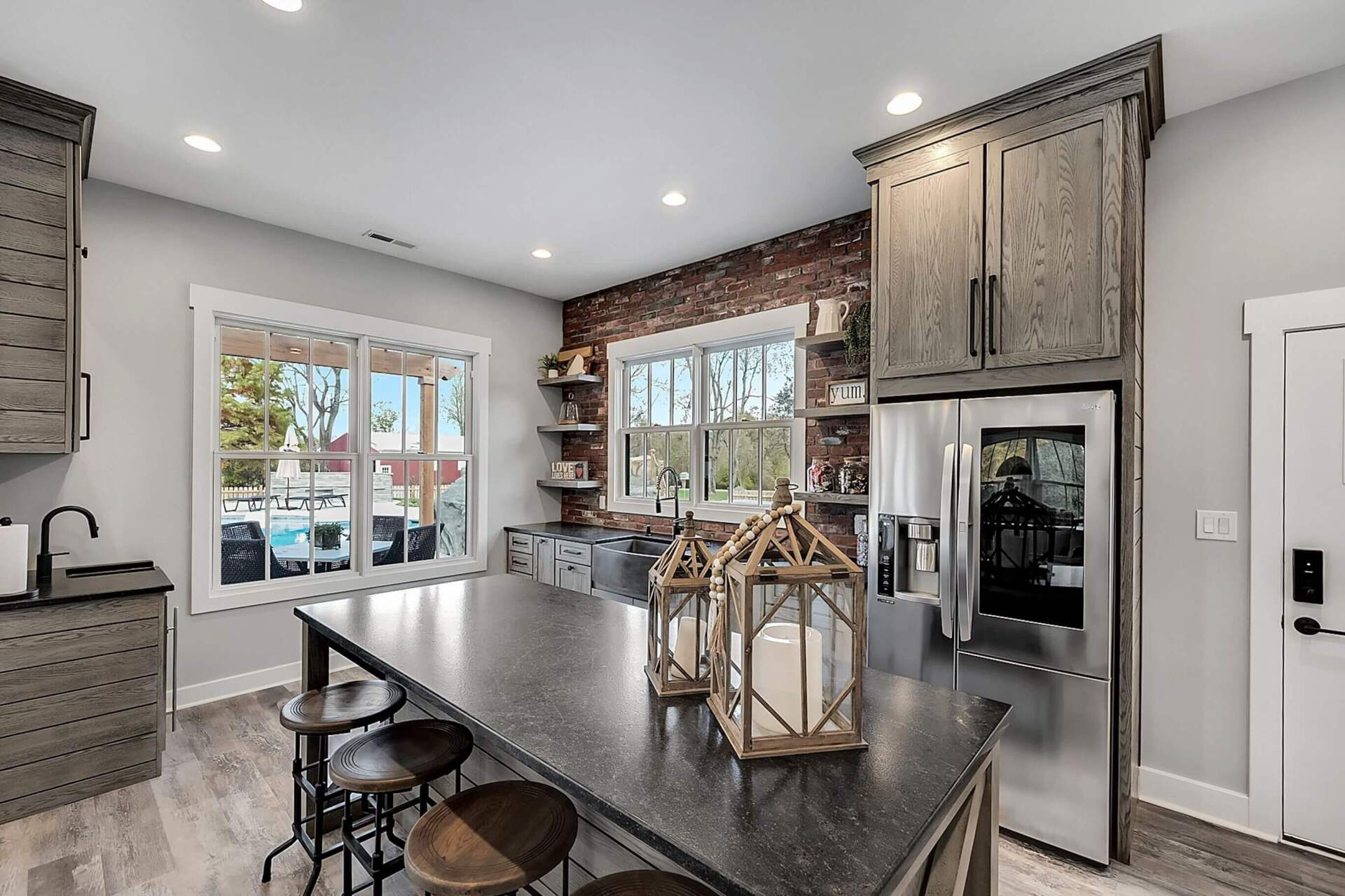 Modern kitchen with island, stools, wood cabinets, brick backsplash, and stainless steel appliances