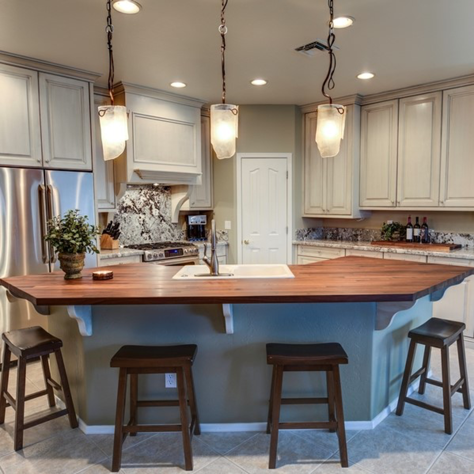 Bright modern kitchen with a large wooden island, hanging pendant lights, and stools