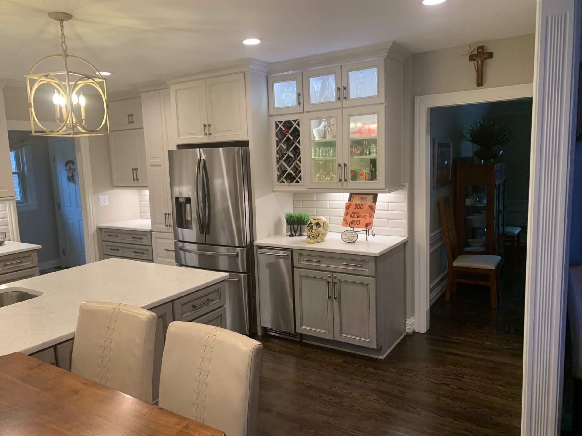 Modern kitchen with white cabinets, stainless steel fridge, island, and dark wood floors