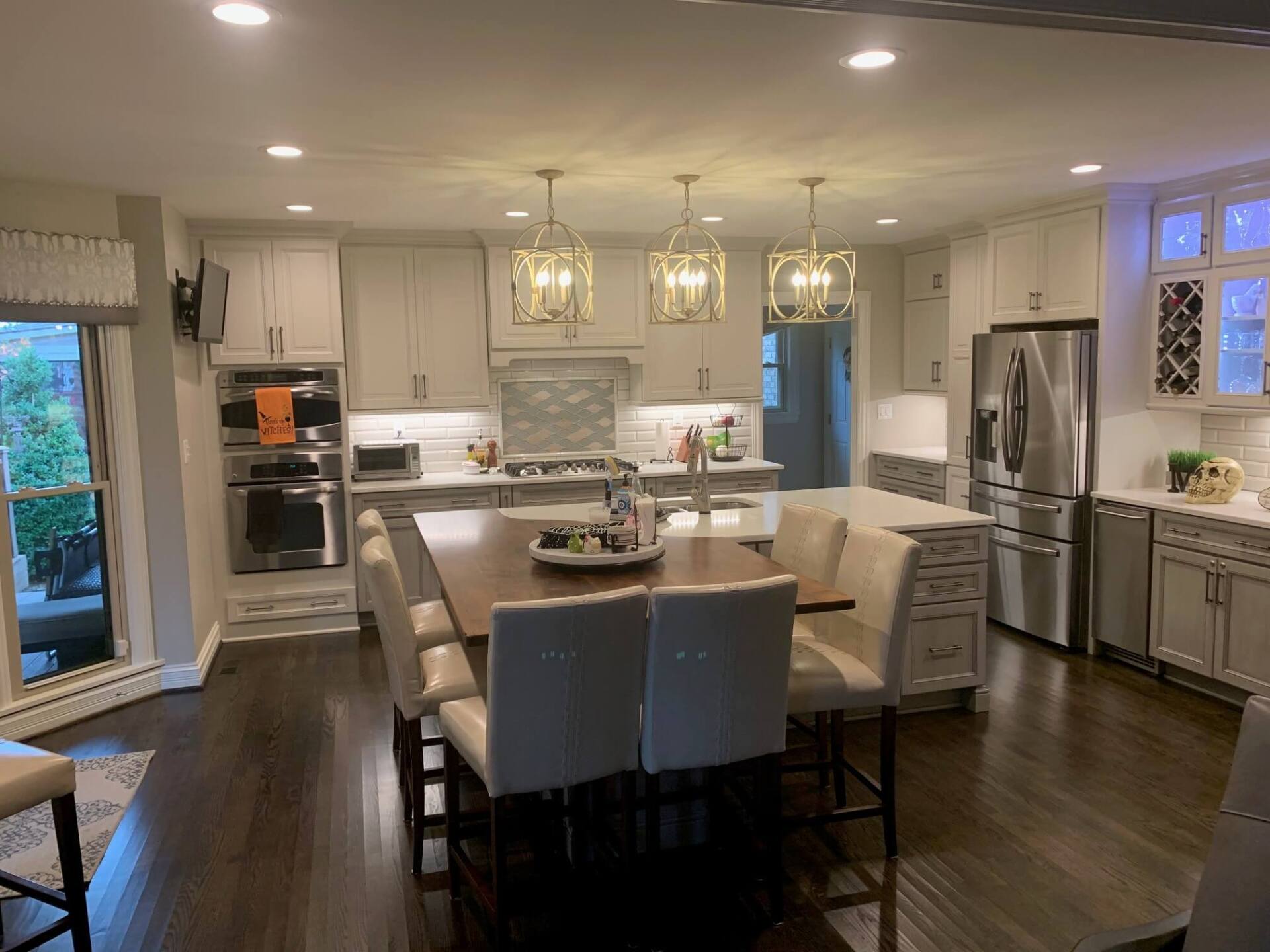 Modern kitchen with white cabinets, stainless appliances, island seating, and dark wood floors
