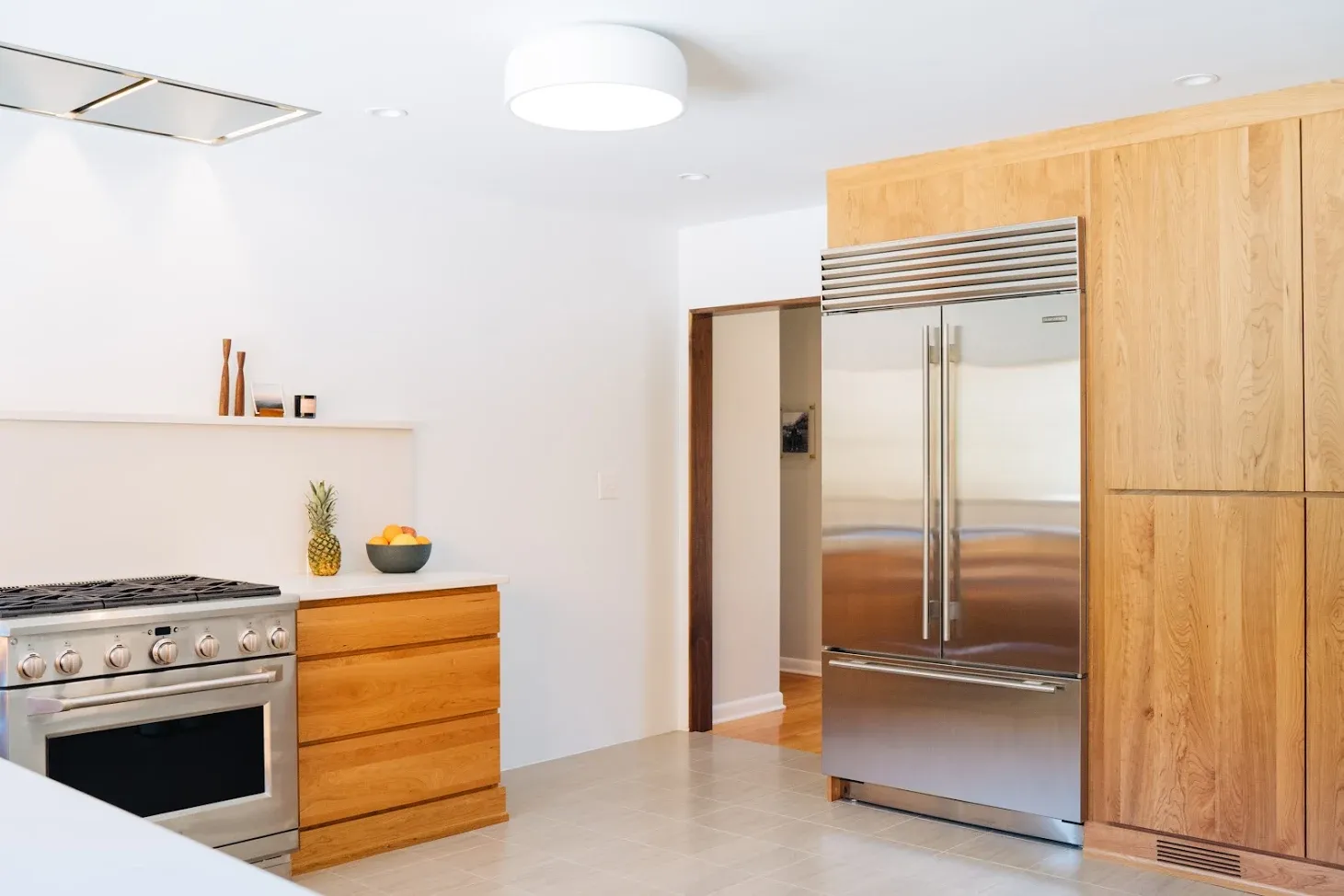 Modern kitchen with stainless steel appliances, wood cabinets, and bright white walls