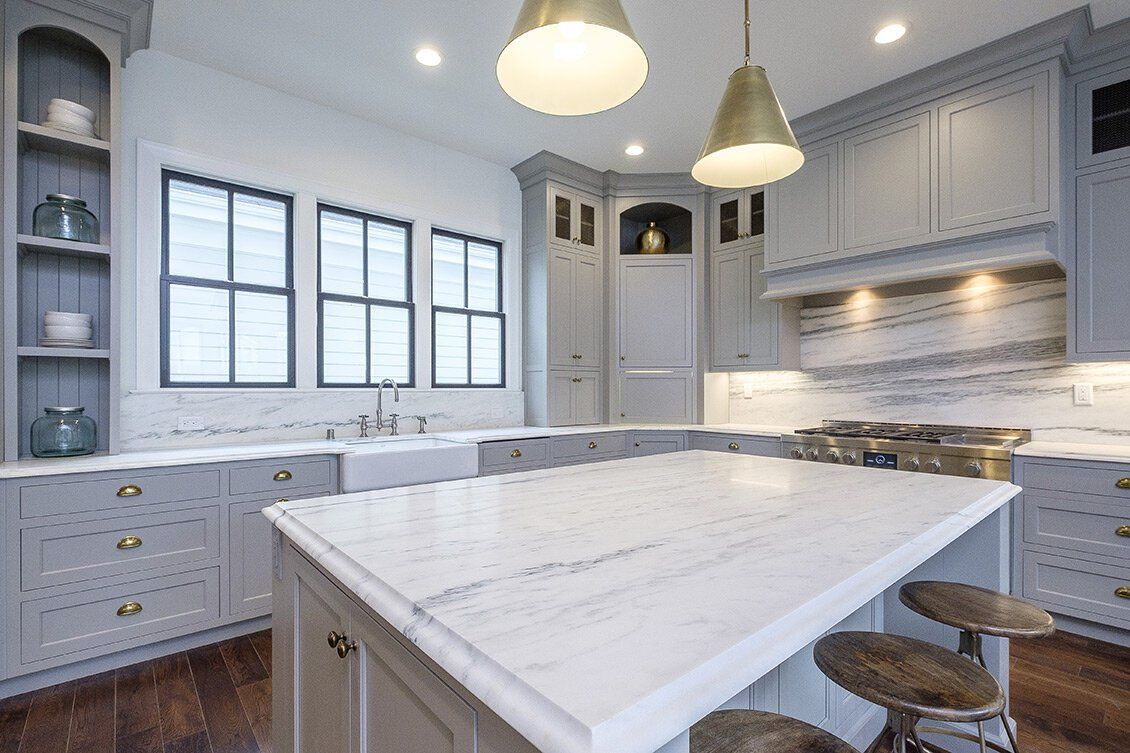 Bright modern white kitchen with marble island, pendant lights, and built-in cabinets