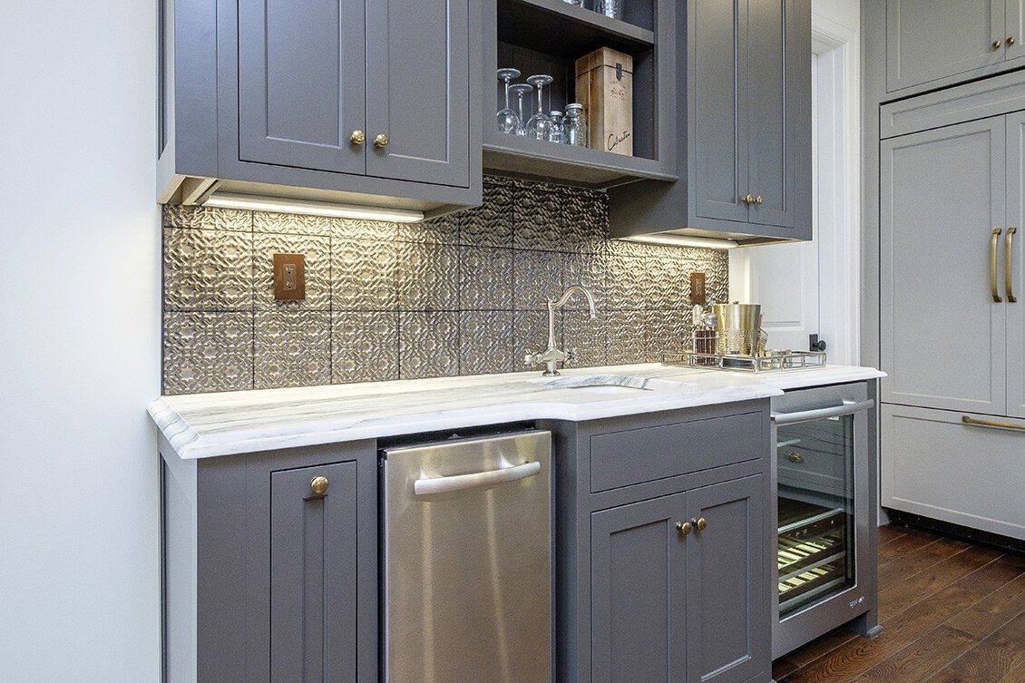 Modern kitchen with gray cabinets, white countertop, stainless dishwasher, and mosaic tile backsplash
