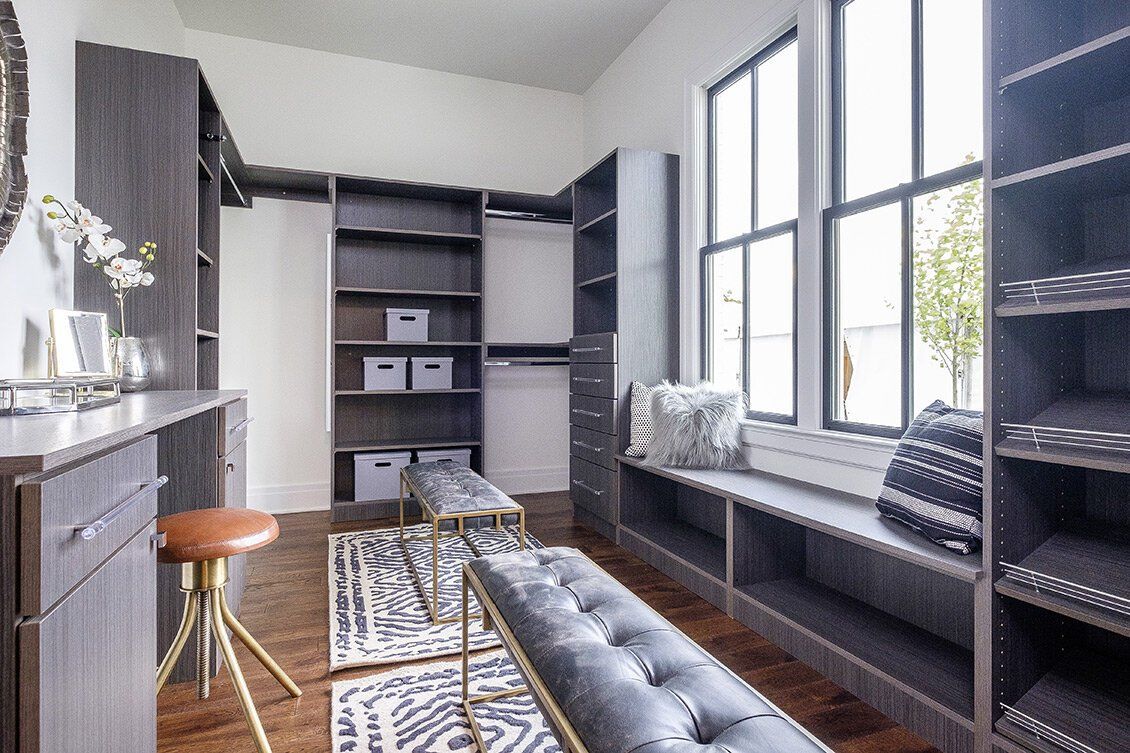 Modern home office with gray built-ins, window seat, desk, and patterned rug in a bright room