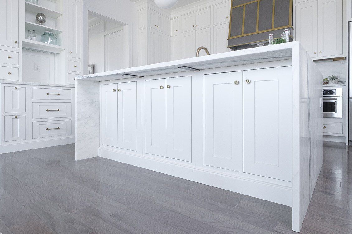 Bright white kitchen with cabinets, island, and gray floor in a modern home