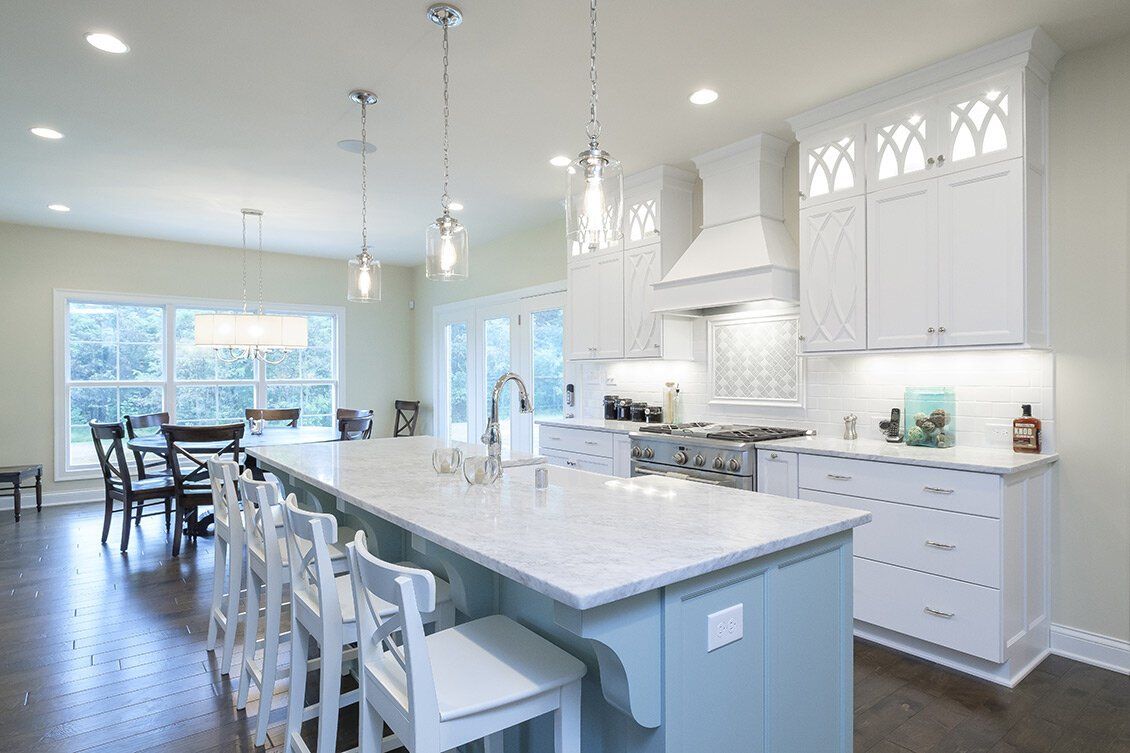 Bright white modern kitchen with a large island, pendant lights, and open dining area