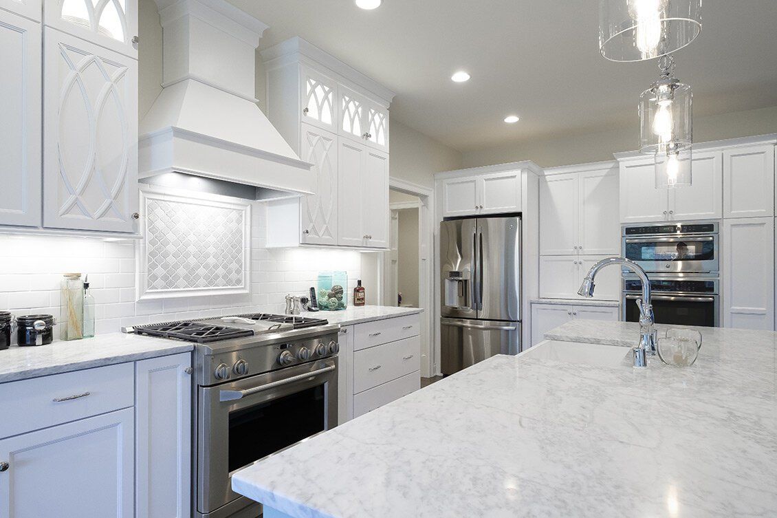 Bright white modern kitchen with stainless steel appliances and large marble island
