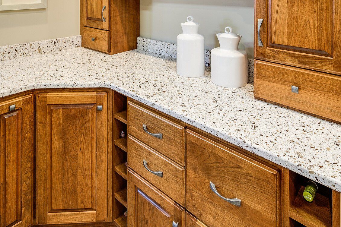Speckled granite kitchen countertop with wooden cabinets and white canisters