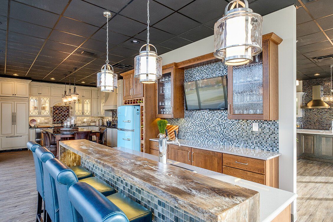 Modern kitchen with blue barstools, granite island, pendant lights, and mosaic tile backsplash