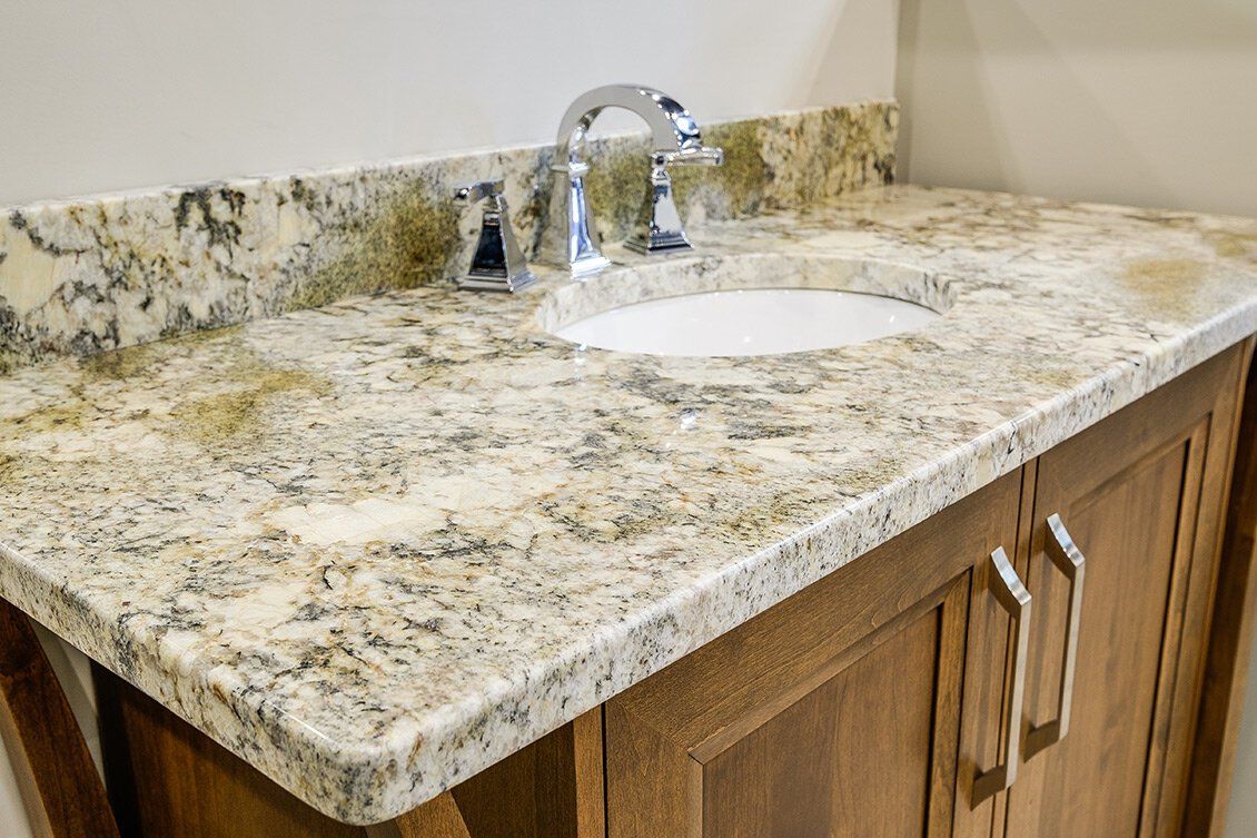 Granite bathroom vanity with oval sink and chrome faucet, viewed from the corner.