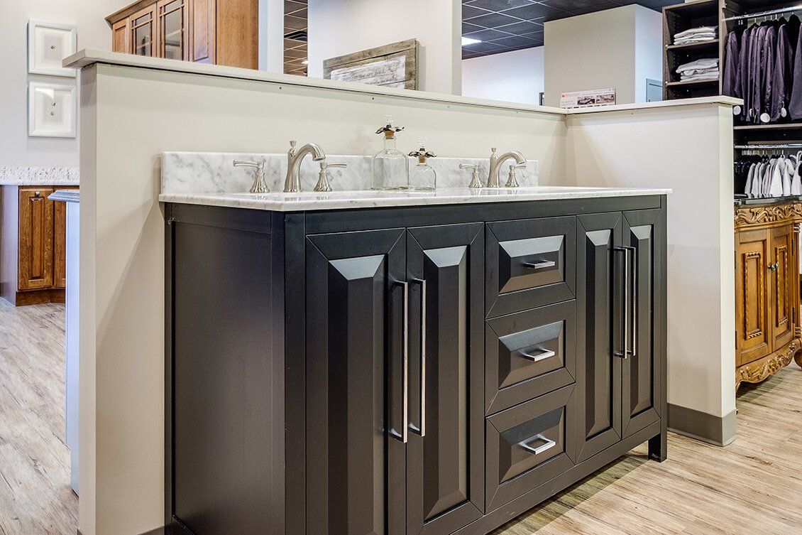 Dark wood kitchen island with a white countertop and built-in sink in a bright showroom kitchen.