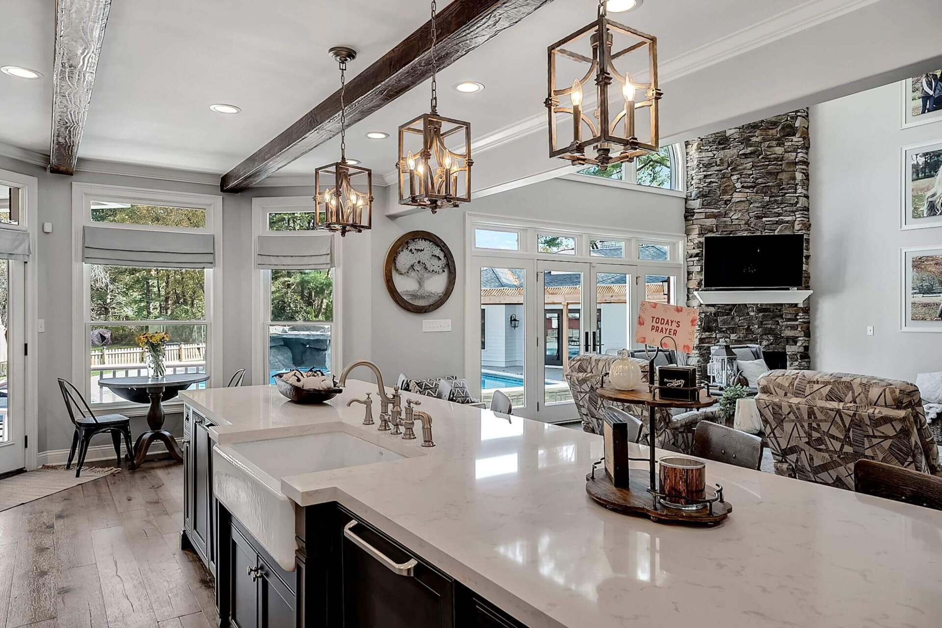 Bright modern kitchen with white island, hanging lanterns, and dining area by large windows