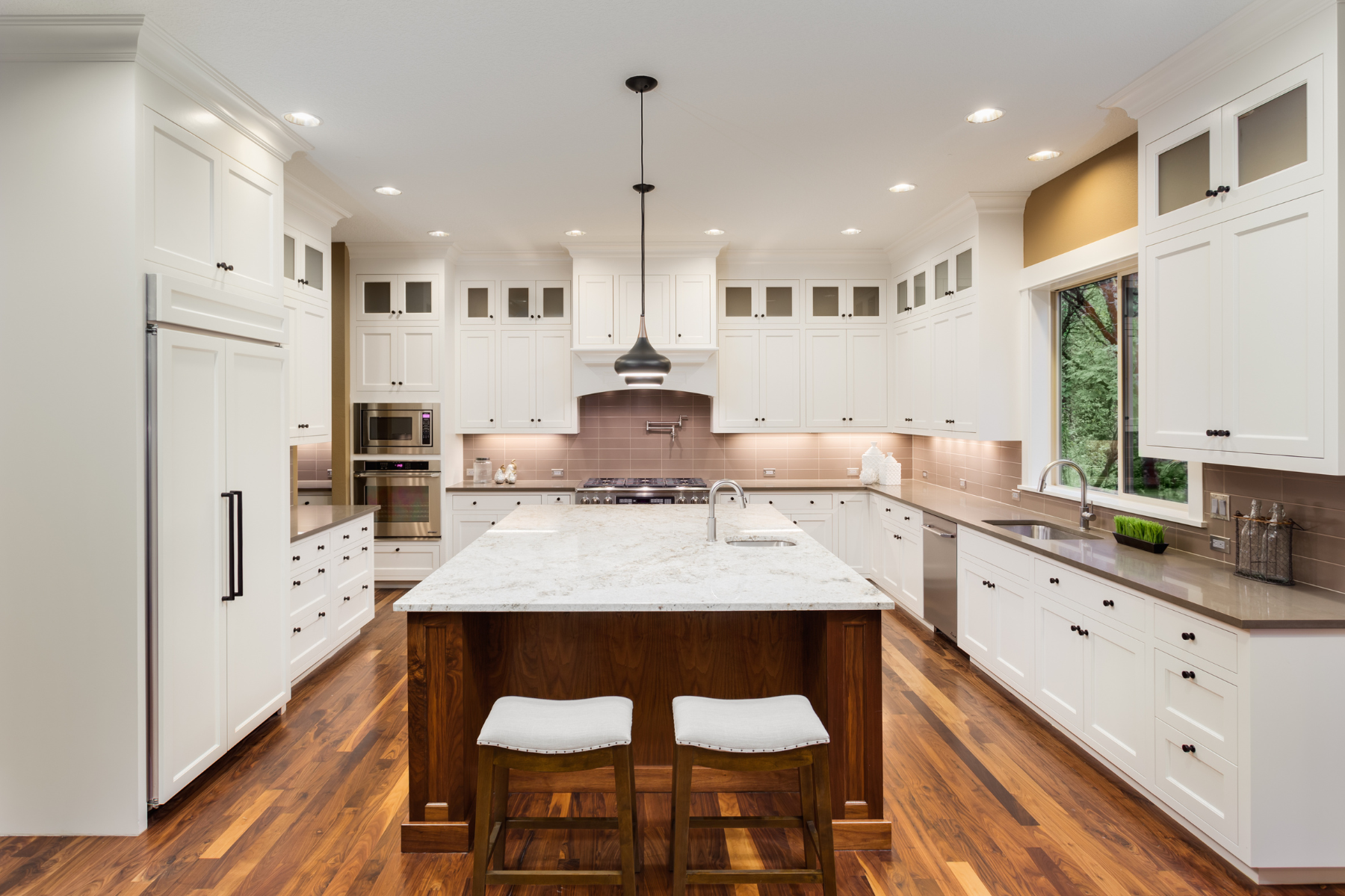 Bright modern kitchen with white cabinets, large island, and hardwood floors