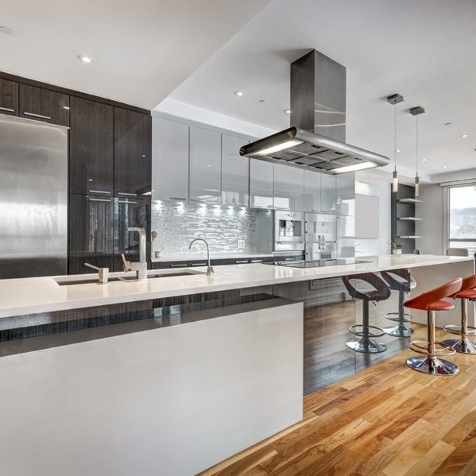 Modern kitchen with white island, stainless-steel appliances, glass cabinets, and hardwood floors
