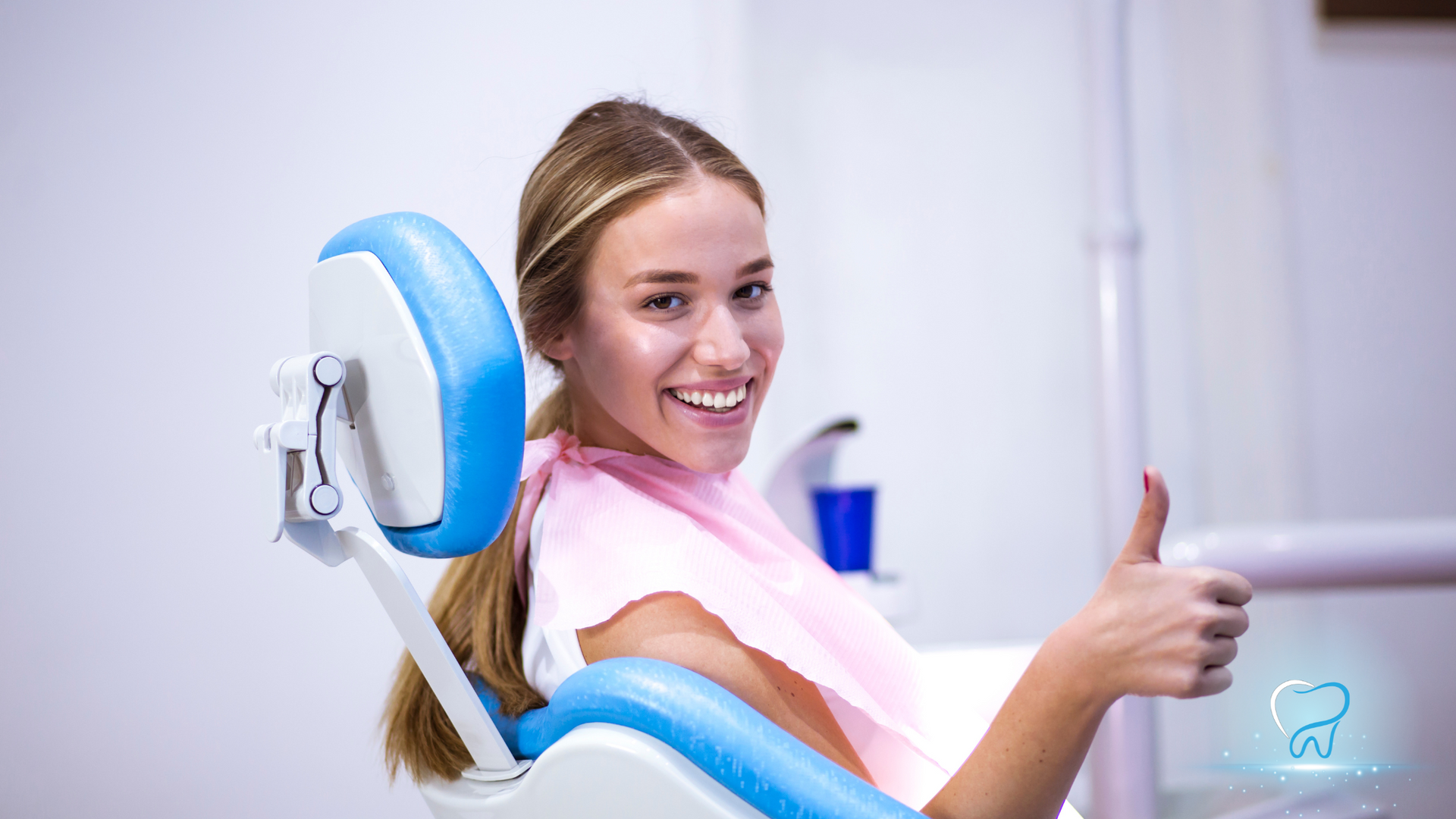 Smiling dental patient in a chair giving a thumbs-up in a bright clinic