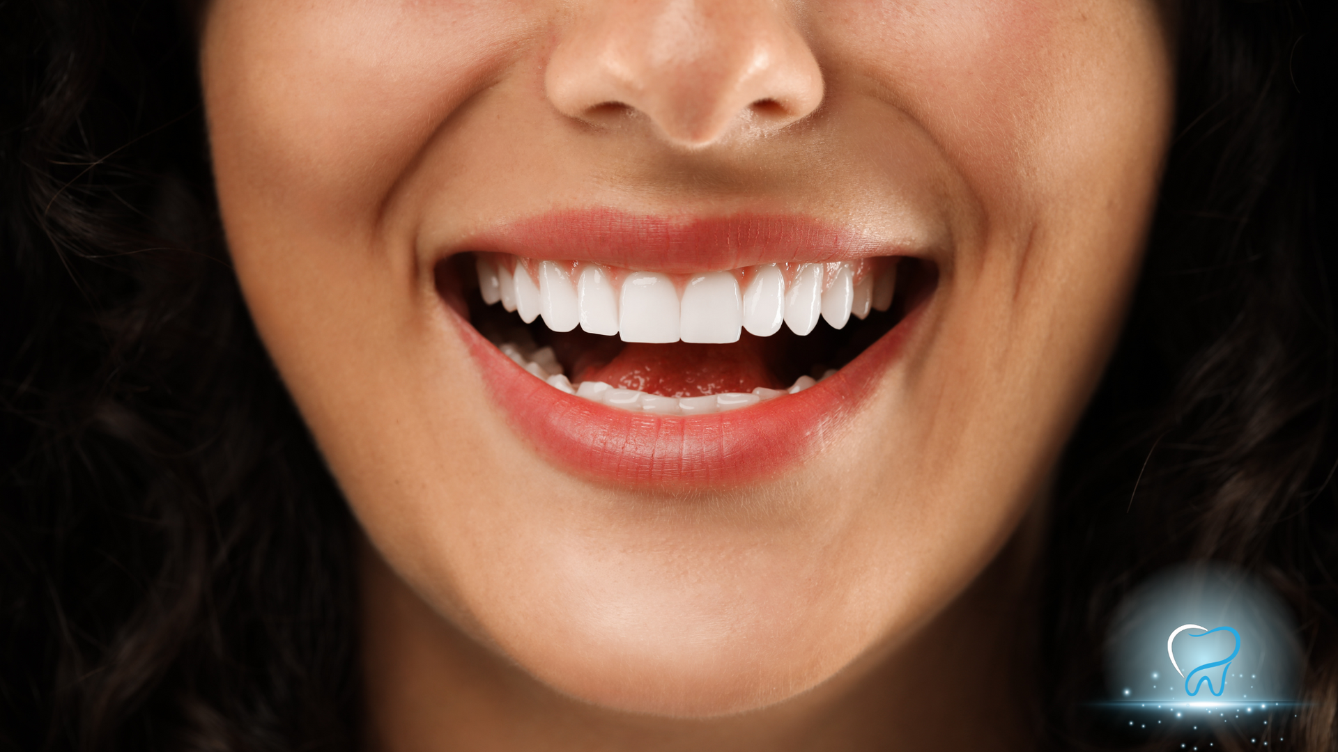 Close-up of a smiling mouth with bright white teeth and glossy red lipstick