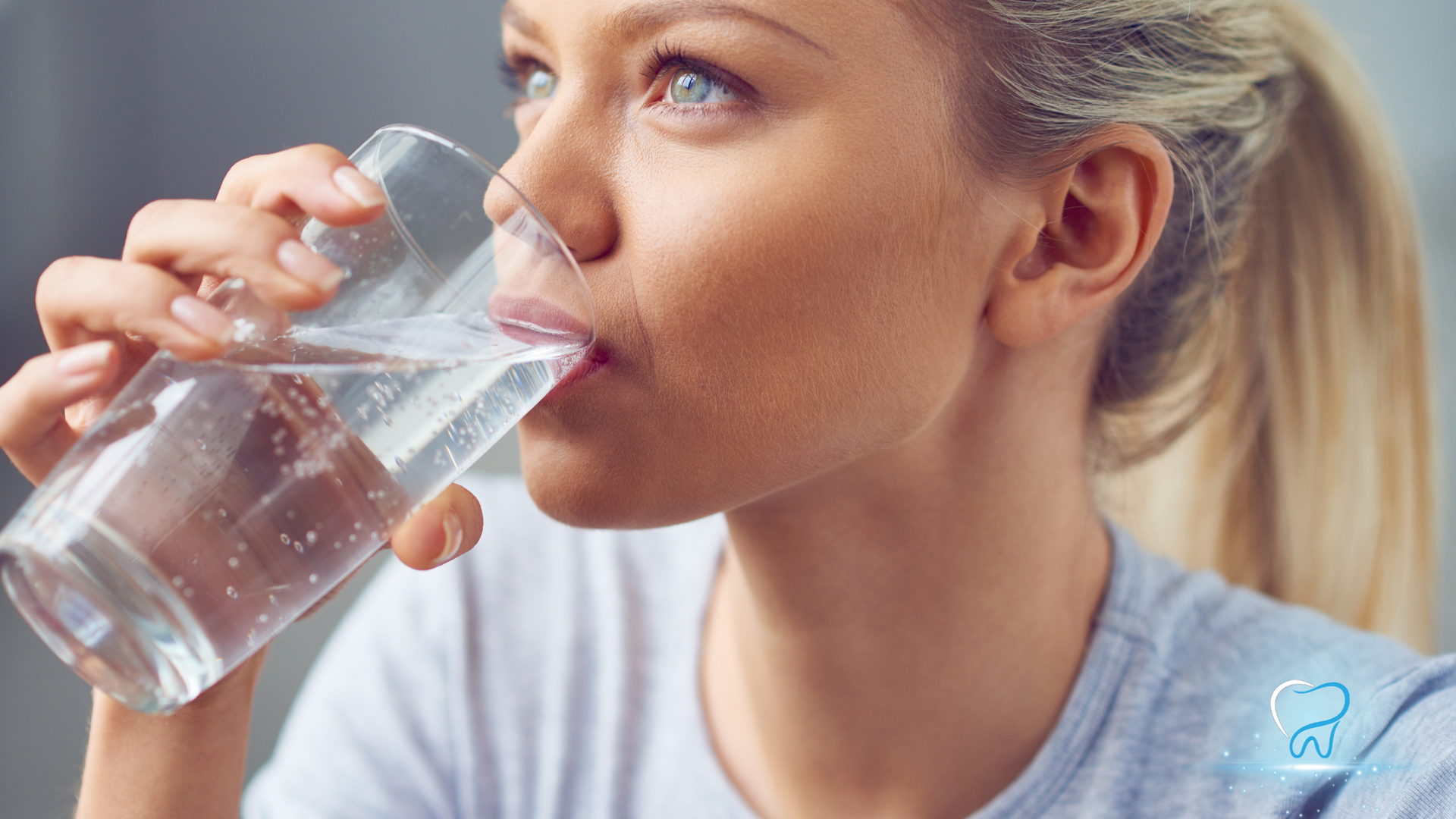 Woman drinking water from a glass, close-up side view in a bright indoor setting