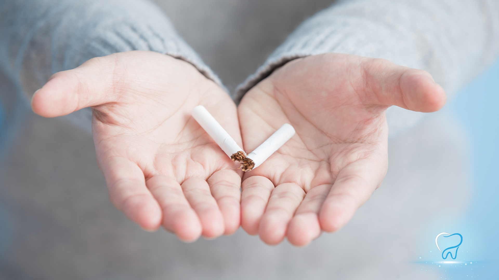 Two open hands holding a broken cigarette, symbolizing quitting smoking