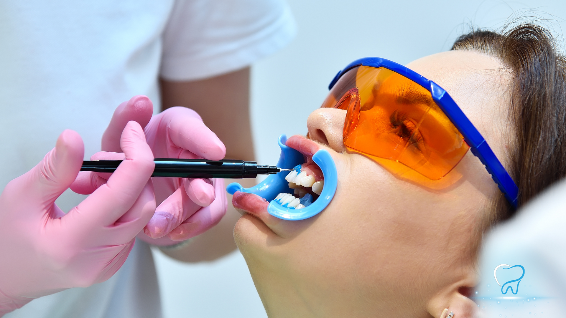 Dentist using a tool on a patient wearing orange protective goggles during a dental procedure