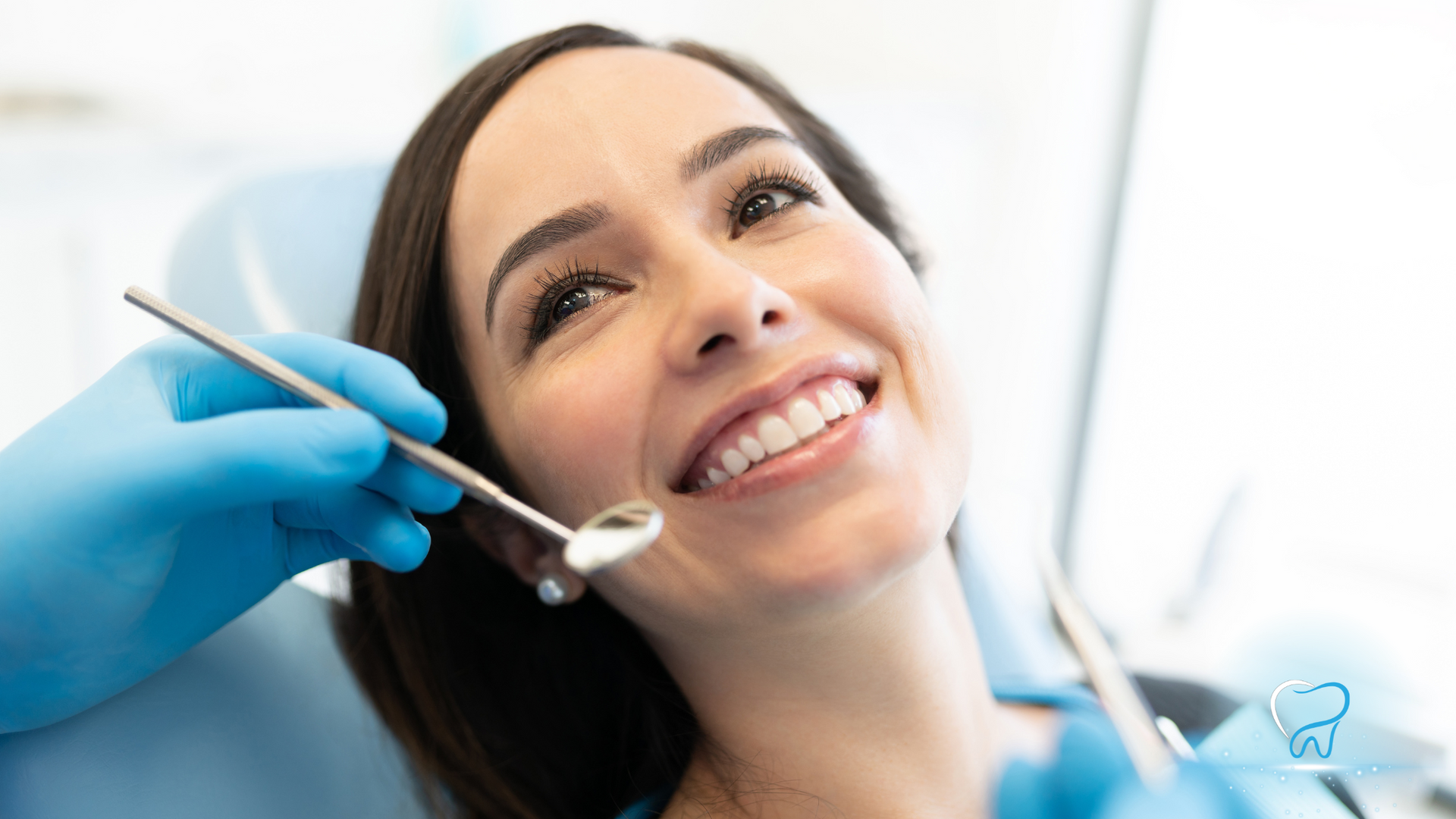 Smiling patient receiving a dental exam from a dentist wearing blue gloves