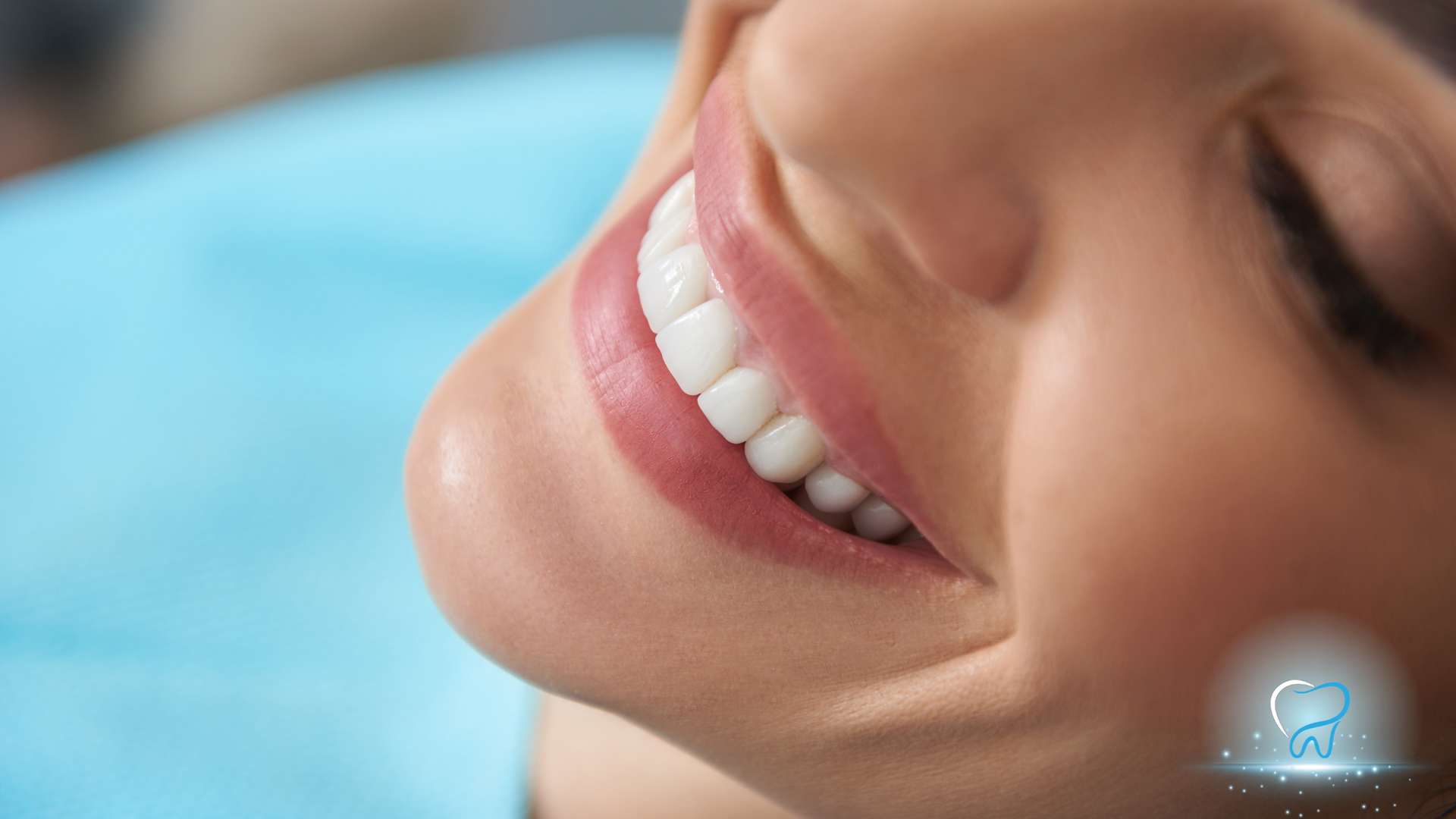 Close-up of a smiling woman’s face, showing white teeth and lips against a blue background