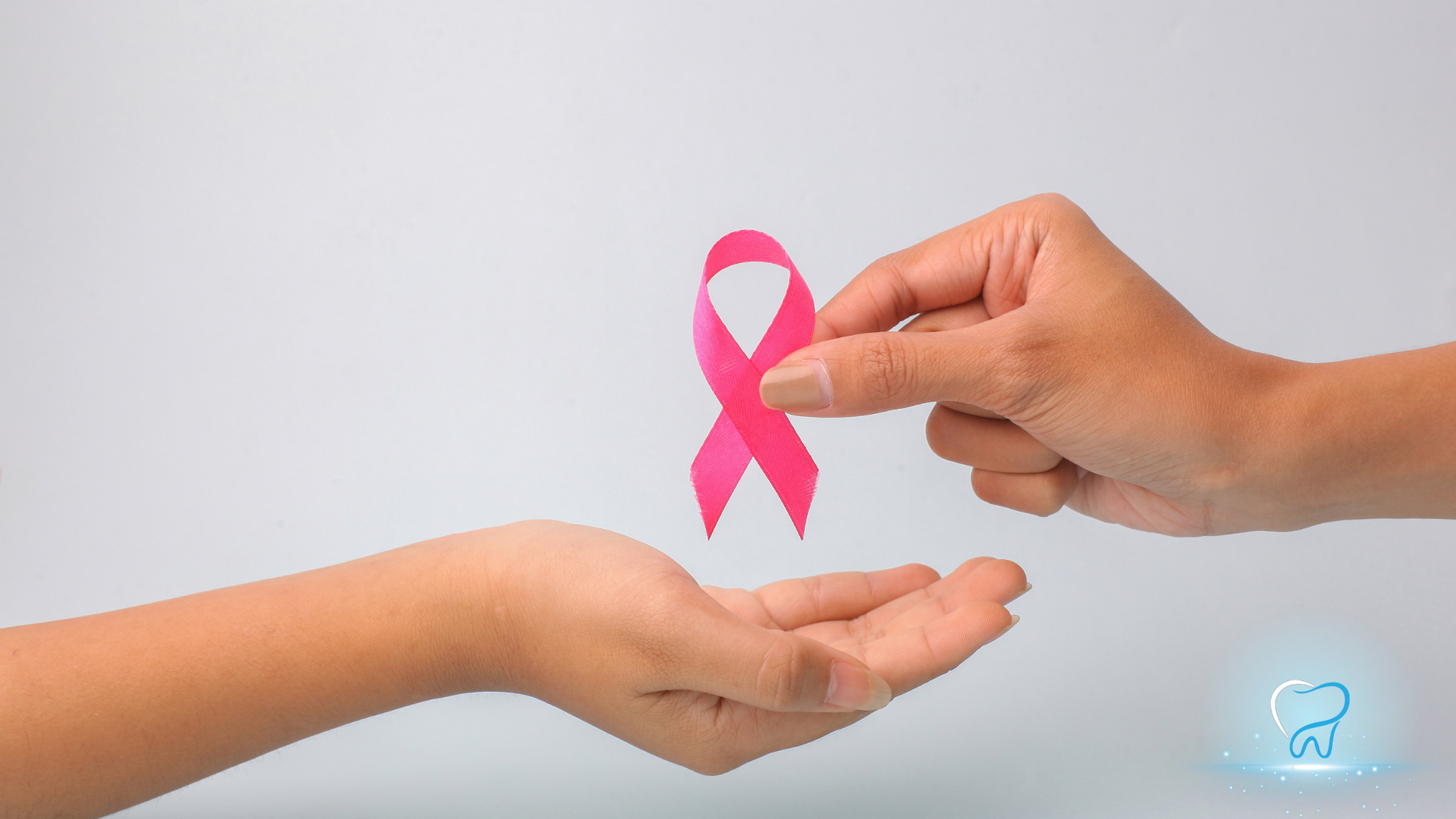 Pink breast cancer awareness ribbon being handed from one person to another on a light background