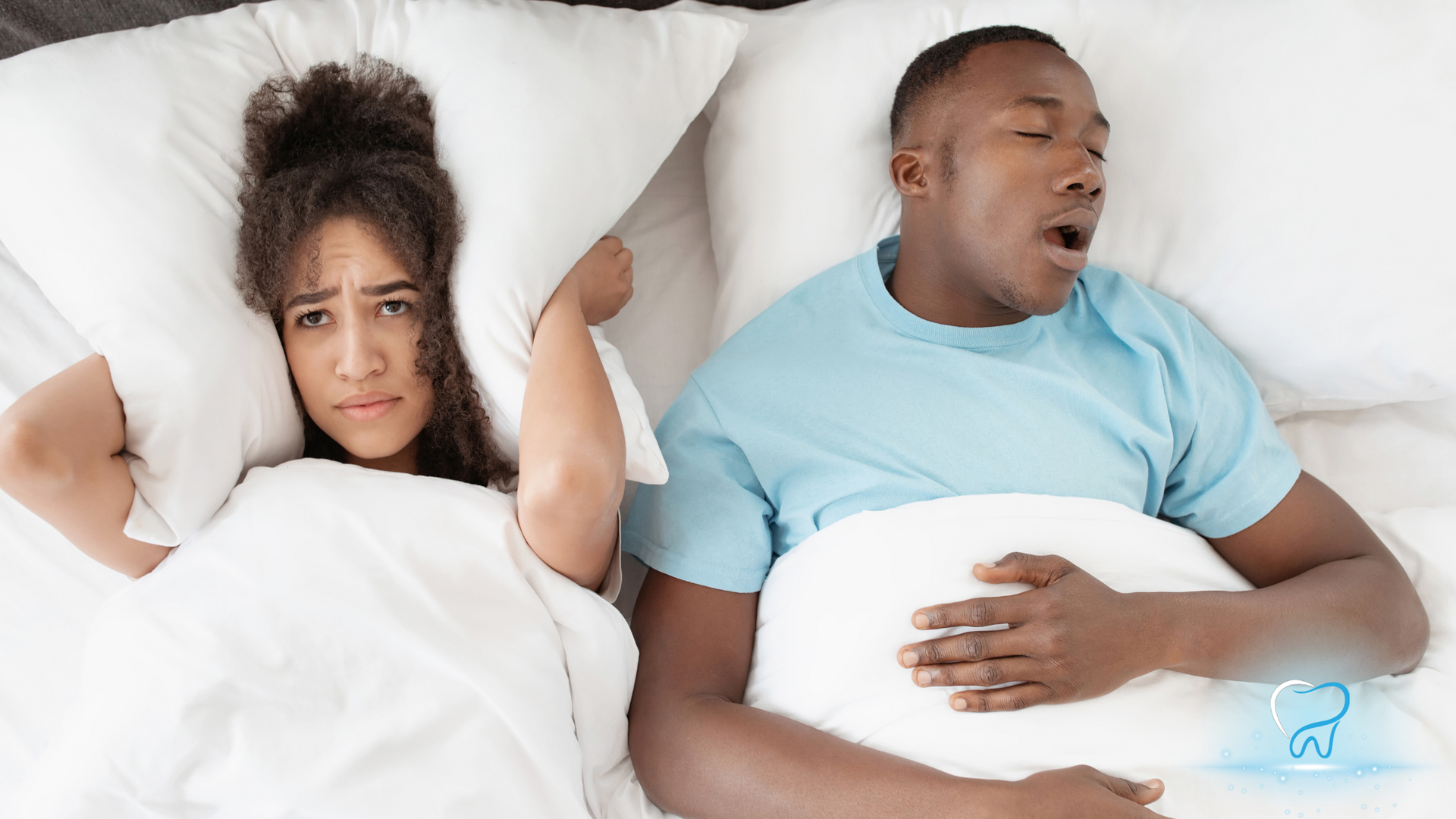 Two people in bed, one awake and frustrated while the other sleeps with mouth open.