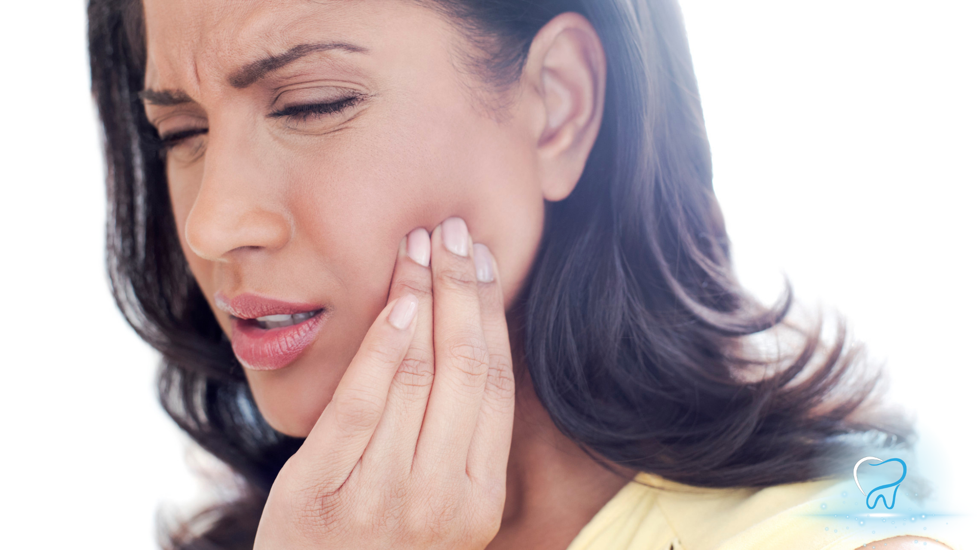 Woman touching her cheek with a pained expression, suggesting toothache or jaw pain.