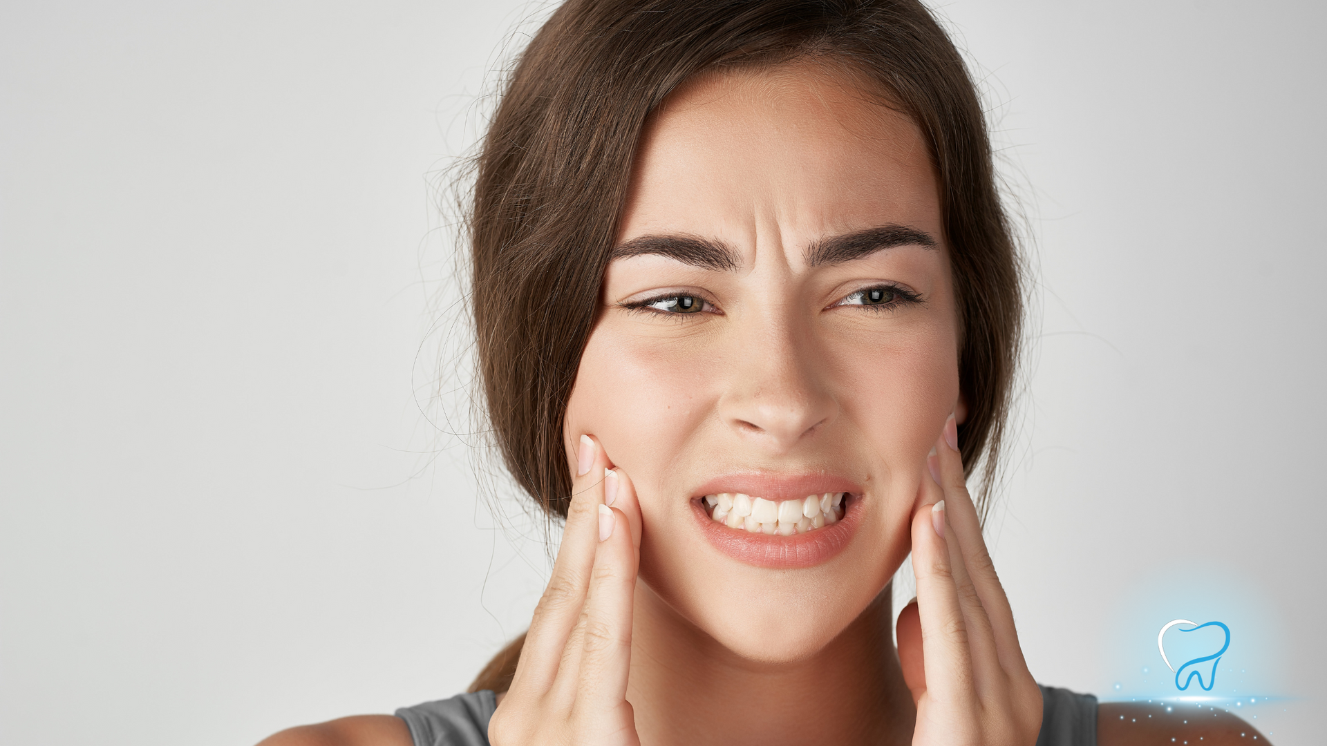Woman pressing cheeks with a pained expression, suggesting toothache or facial pain.
