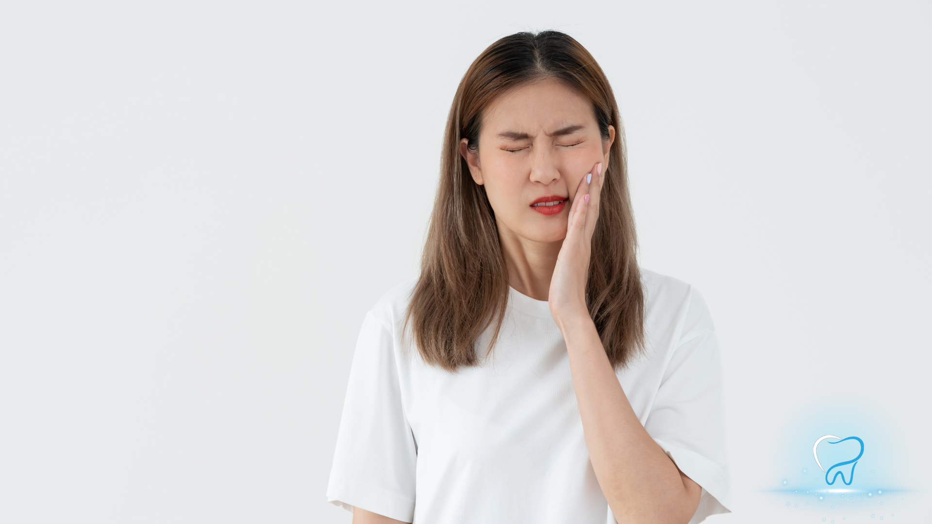 Person holding cheek with a pained expression, wearing a white shirt on a plain white background.