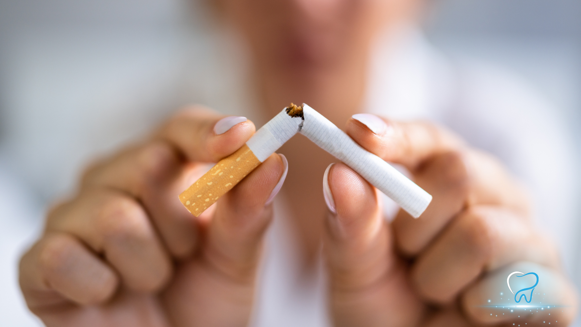 Hands breaking a lit cigarette in half, symbolizing quitting smoking
