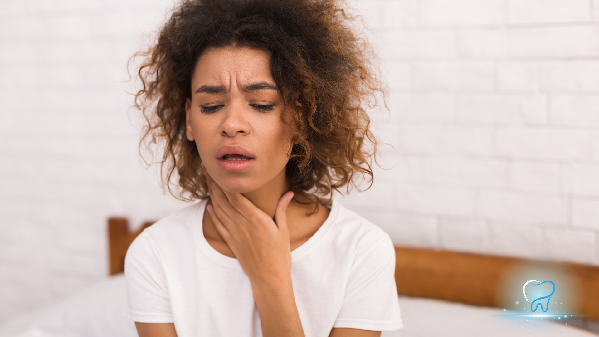 Person in white shirt clutching throat, looking uncomfortable in a bedroom.