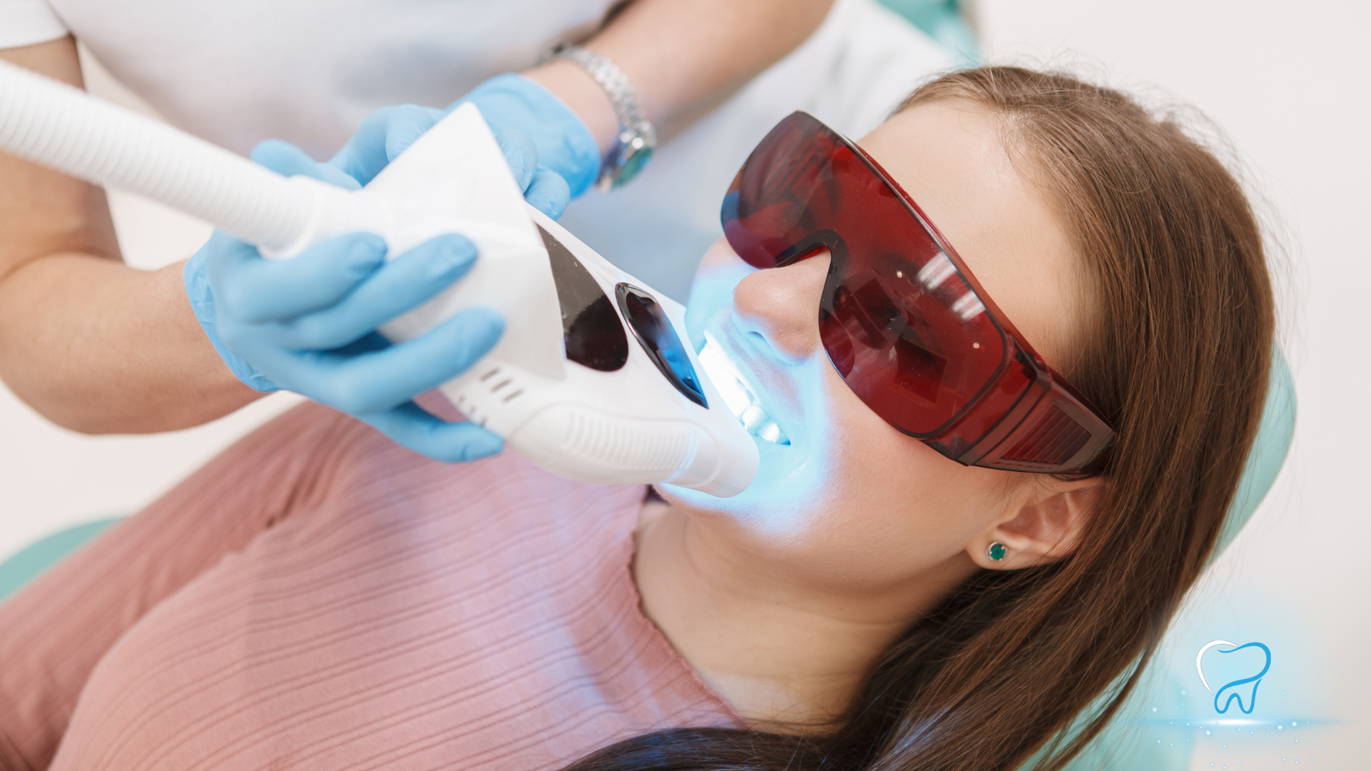 Dentist using a blue-light tool on a patient wearing red protective glasses