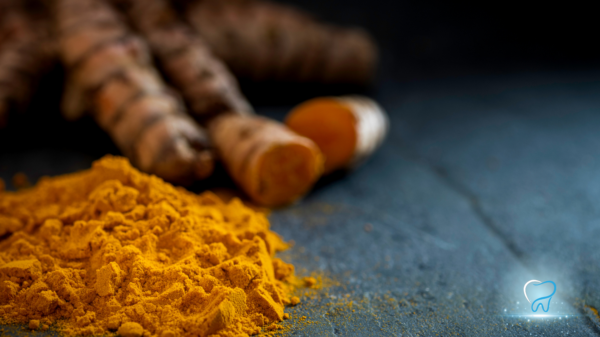 Turmeric powder beside fresh turmeric roots on a dark surface