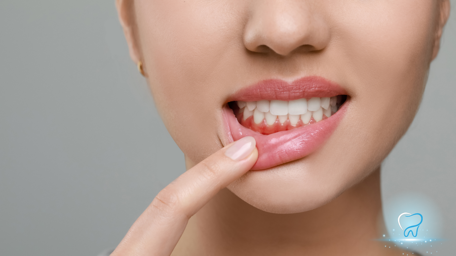 Close-up of a person pointing at their teeth with a finger, showing a tooth gap and discolored teeth.