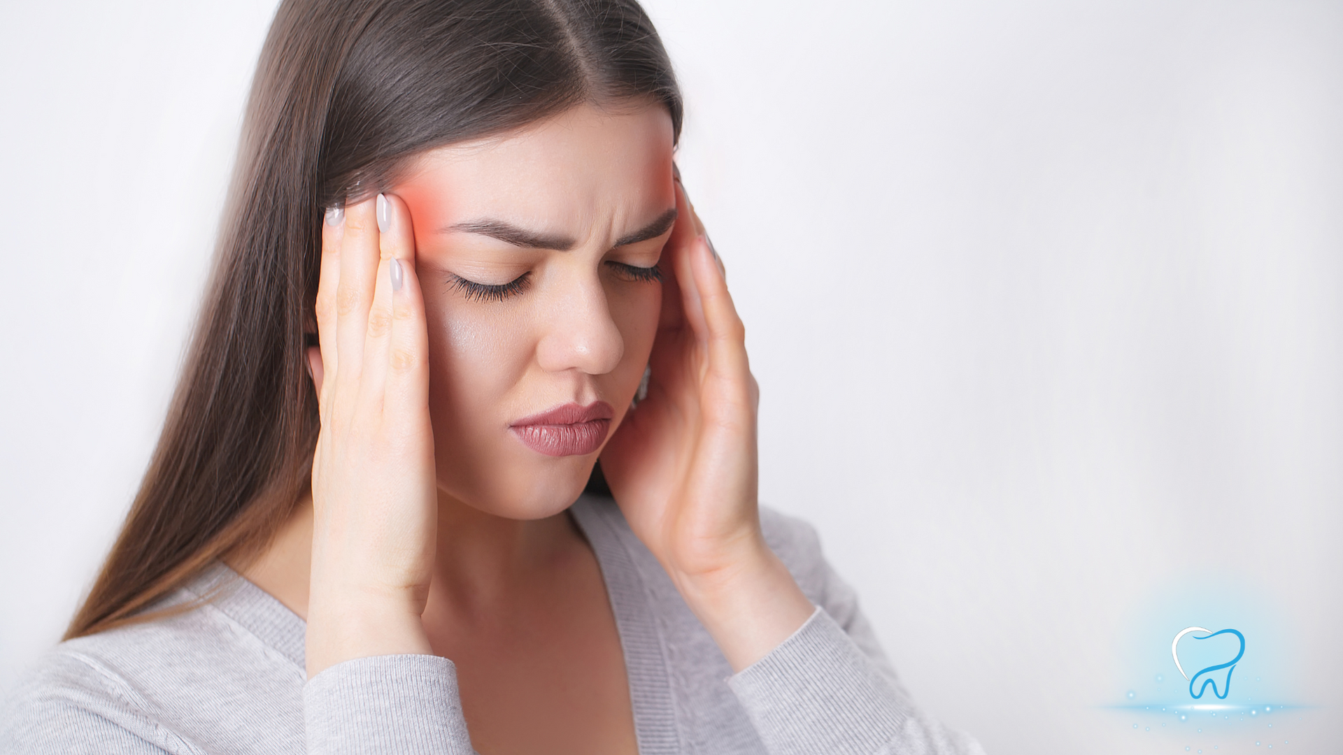 Woman holding her temples with eyes closed, showing discomfort or a headache, on a light background
