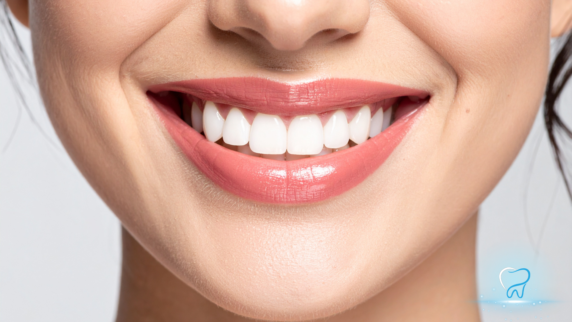 Close-up of a smiling mouth with white teeth and glossy pink lips