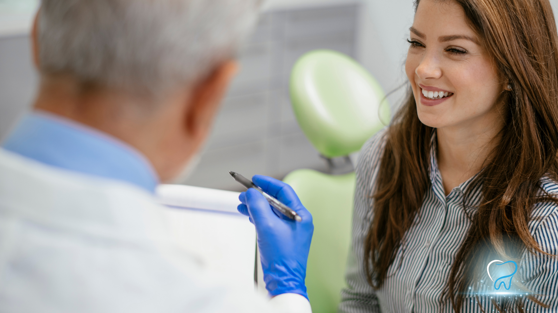 Dentist in blue gloves examining smiling patient in a dental office